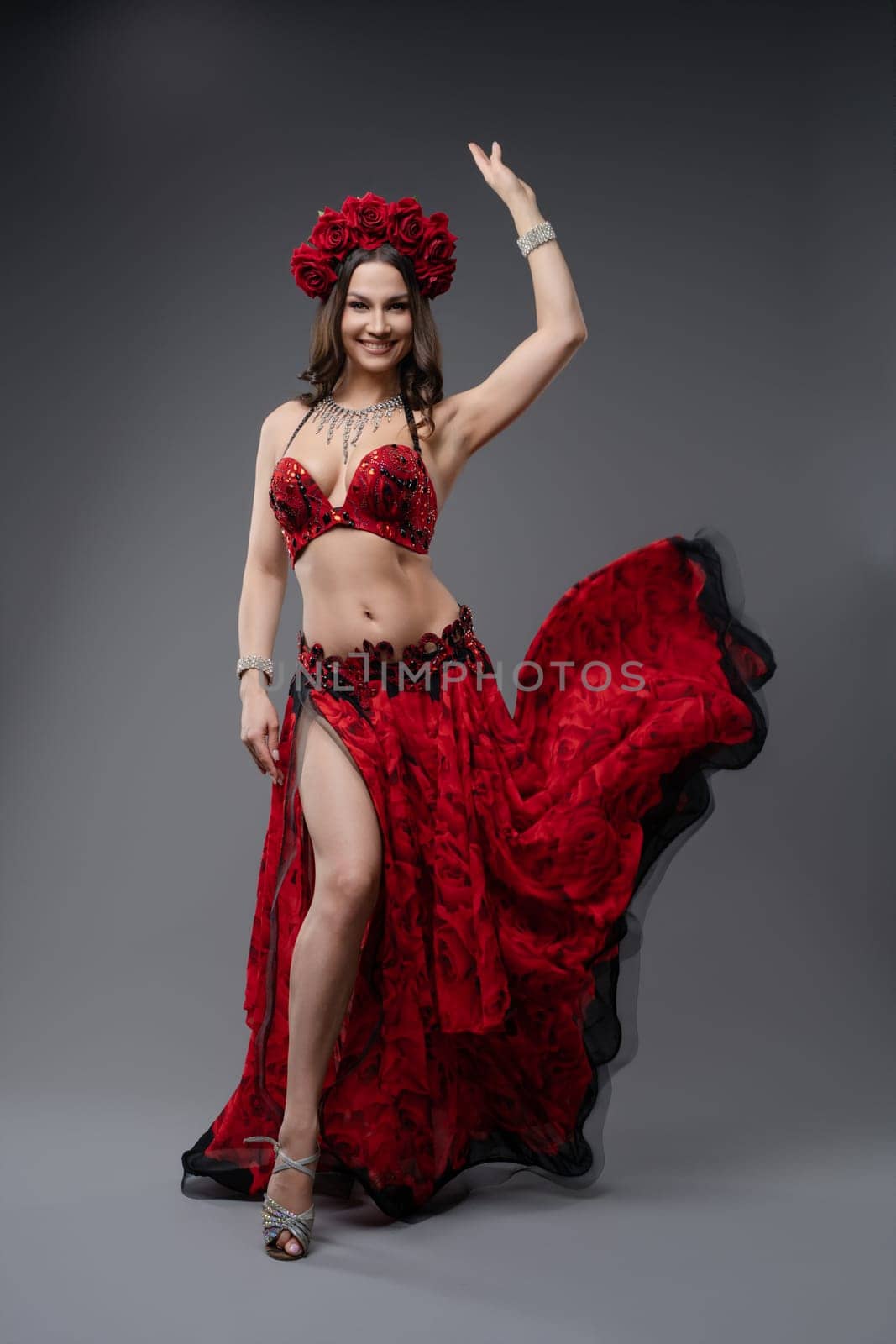 A skilled dancer showcases graceful movements in a stunning red costume complete with flowers, capturing the audience's attention.