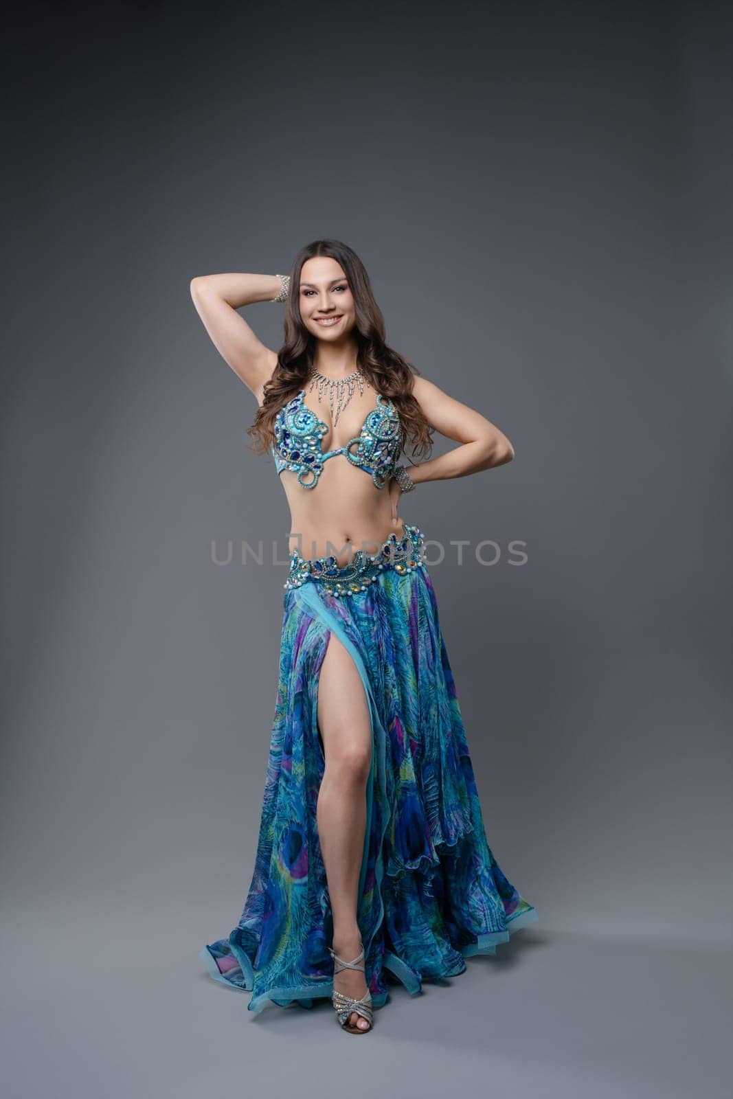 Dancer displays a colorful costume while posing gracefully against a neutral backdrop. The performance highlights her skill and artistry.