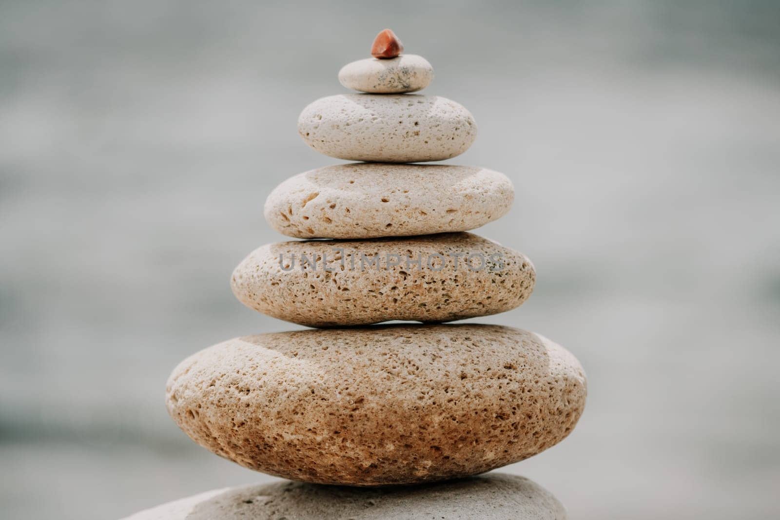 Pyramid stones on the seashore with warm sunset on the sea background. Happy holidays. Pebble beach, calm sea, travel destination. Concept of happy vacation on the sea, meditation, spa, calmness.