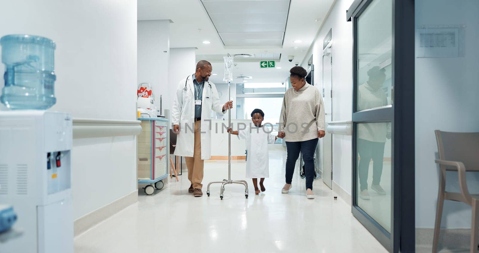 Medical, pediatrician and a doctor walking with a black family in a hospital corridor for diagnosis. Healthcare, communication and consulting with a medicine professional talking to a boy patient.
