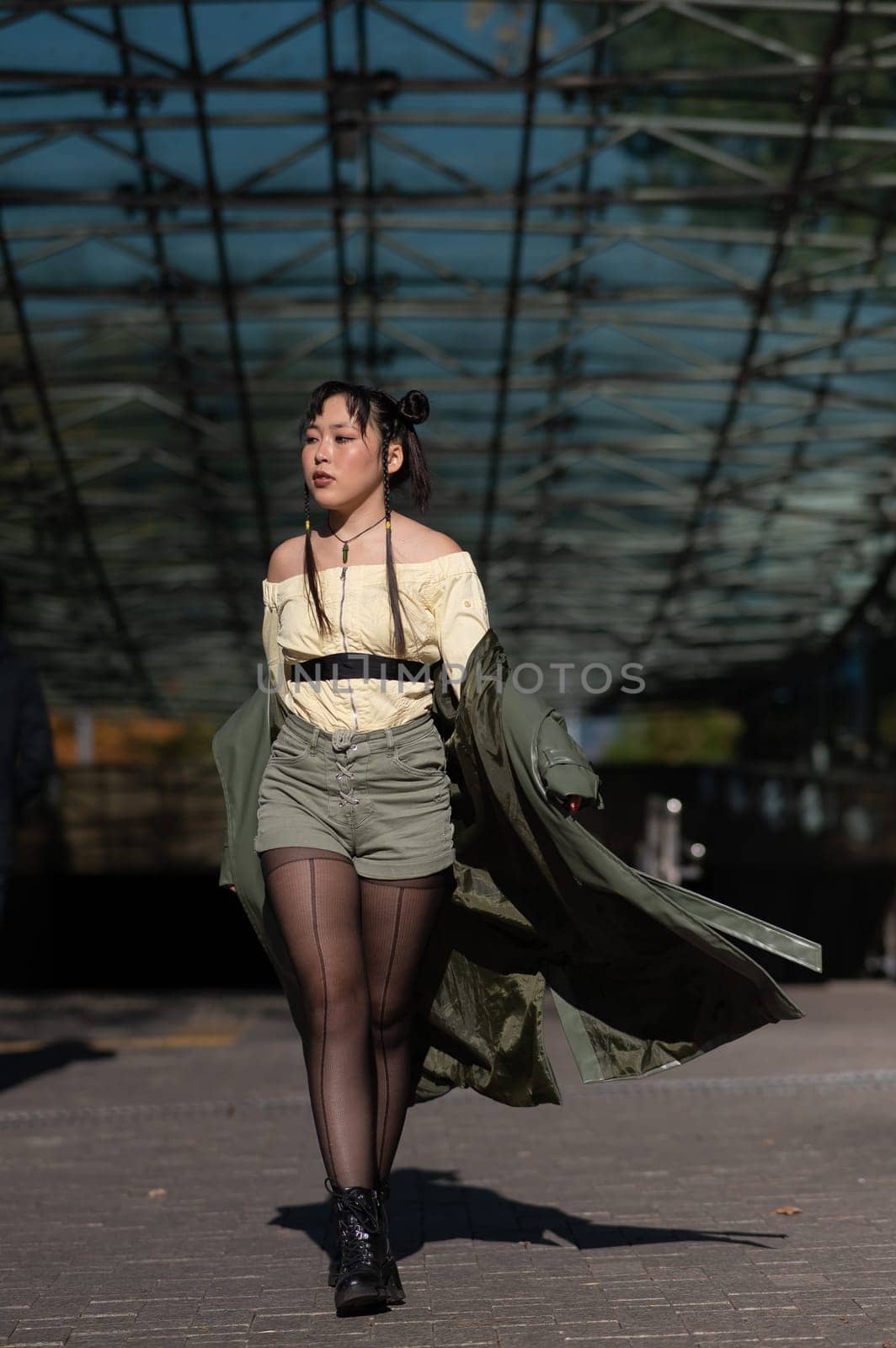 A beautiful Asian woman in shorts and a green leather coat comes out of the subway