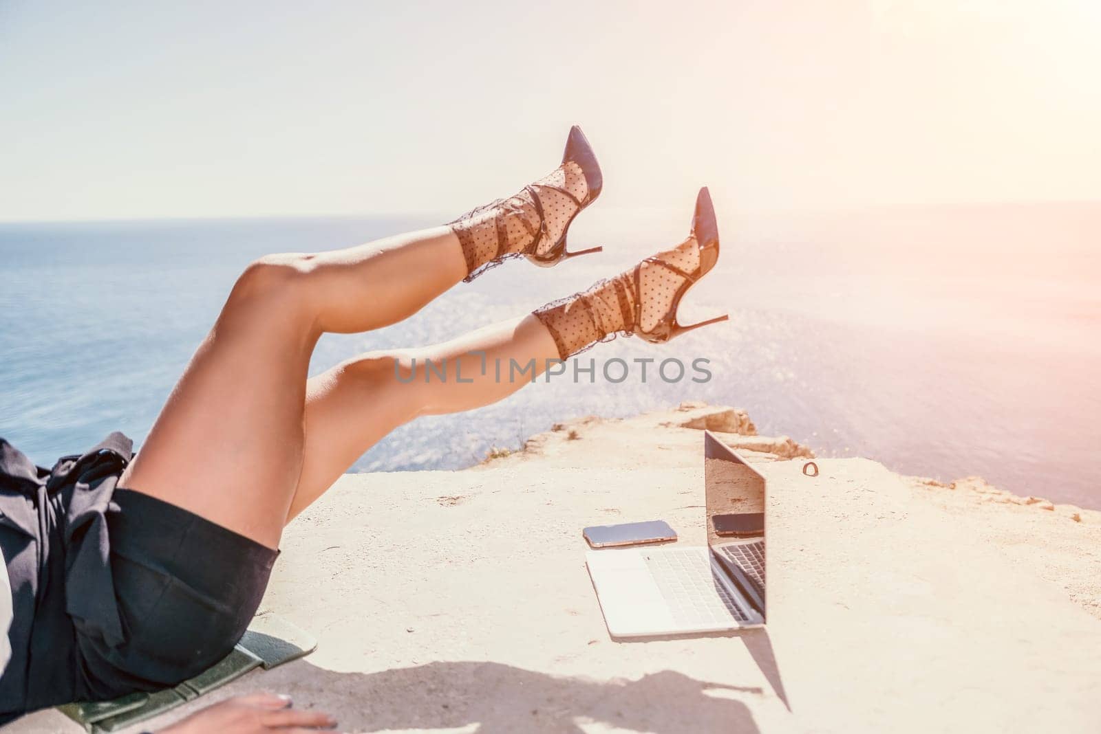 Woman sea laptop. Business woman in yellow hat freelancer with laptop working over blue sea beach. Girl relieves stress from work. Freelance, digital nomad, travel and holidays concept by panophotograph