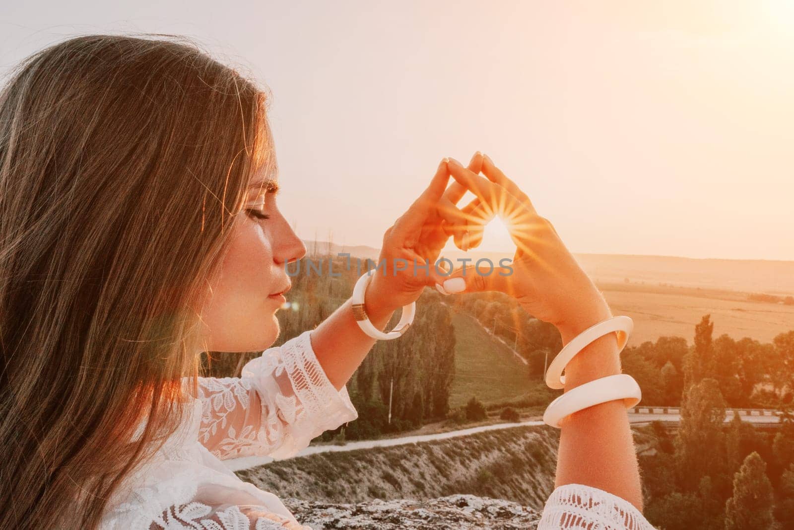 Romantic beautiful bride in white dress posing with sea and mountains in background. Stylish bride standing back on beautiful landscape of sea and mountains on sunset