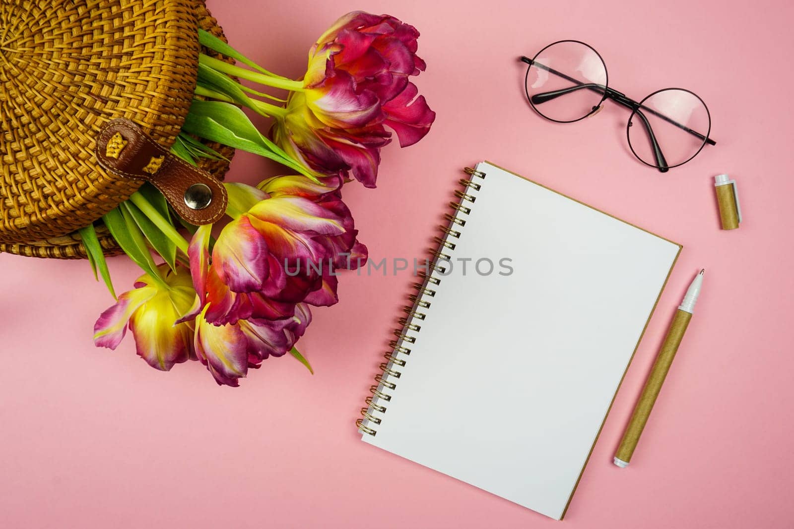 a notebook for notes and pink tulips in a wicker bag. High quality photo