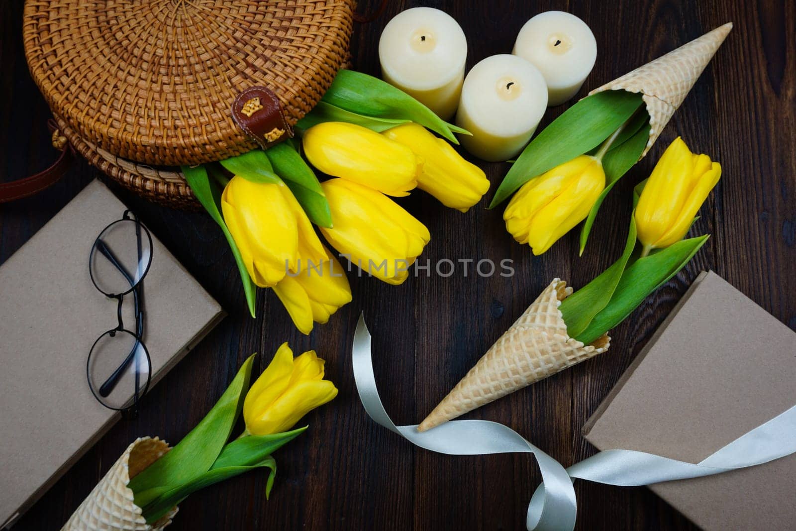 Yellow tulips comfortably laid out on the table in a wicker bag and in waffle cones by Spirina