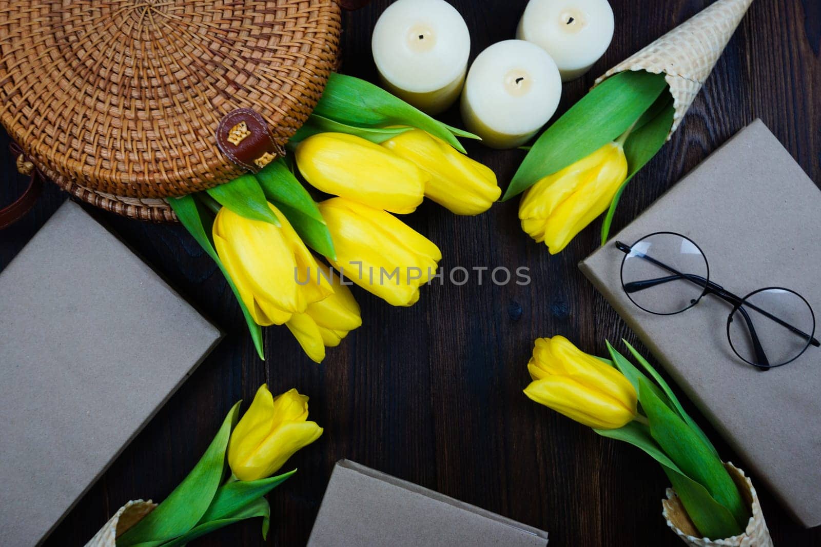 Yellow tulips comfortably laid out on the table in a wicker bag and in waffle cones by Spirina