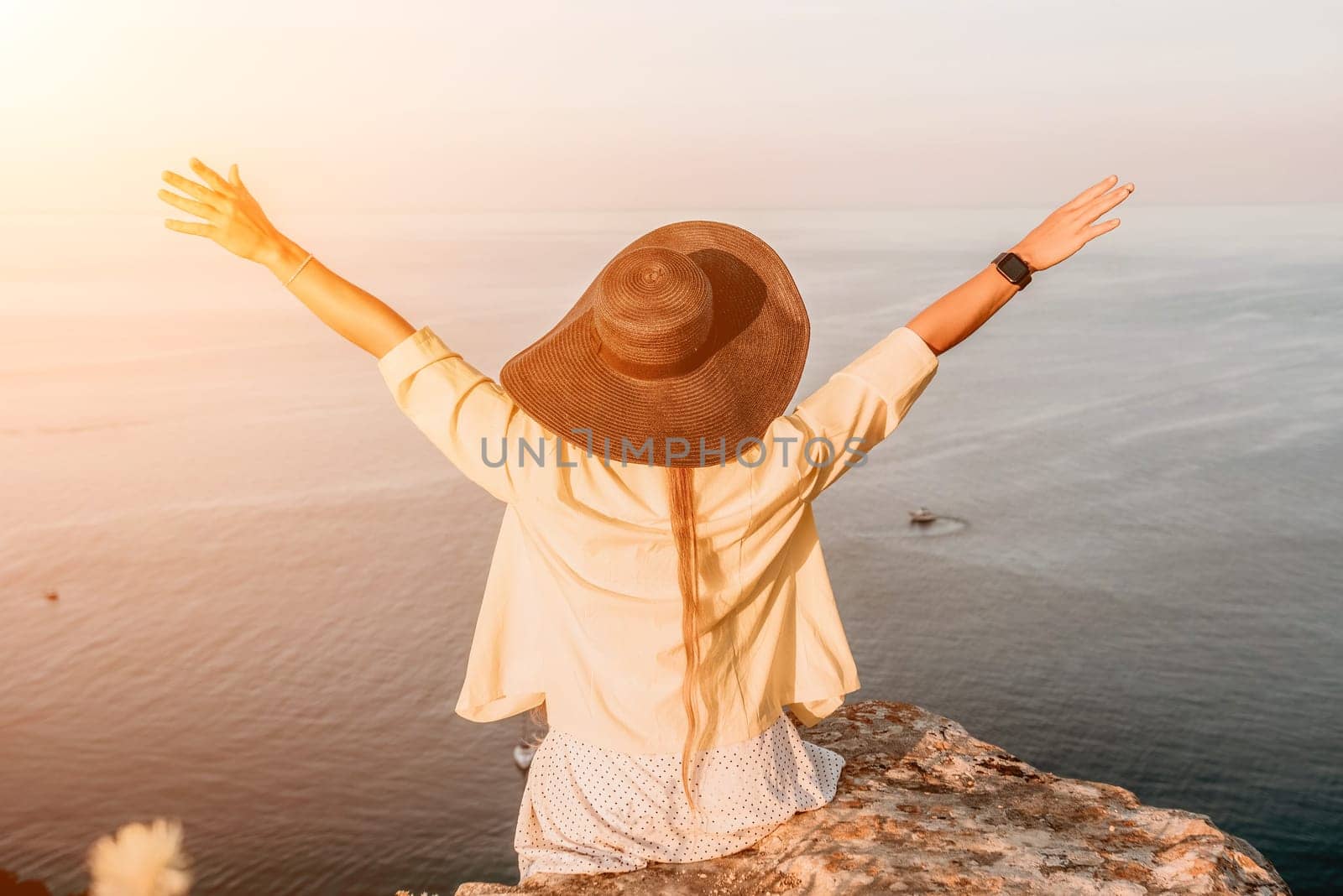 Portrait of happy young woman wearing summer black hat with large brim at beach on sunset. Sensual girl covering half face with hat on beach. Happy young woman smiling and looking at camera at sea. by panophotograph