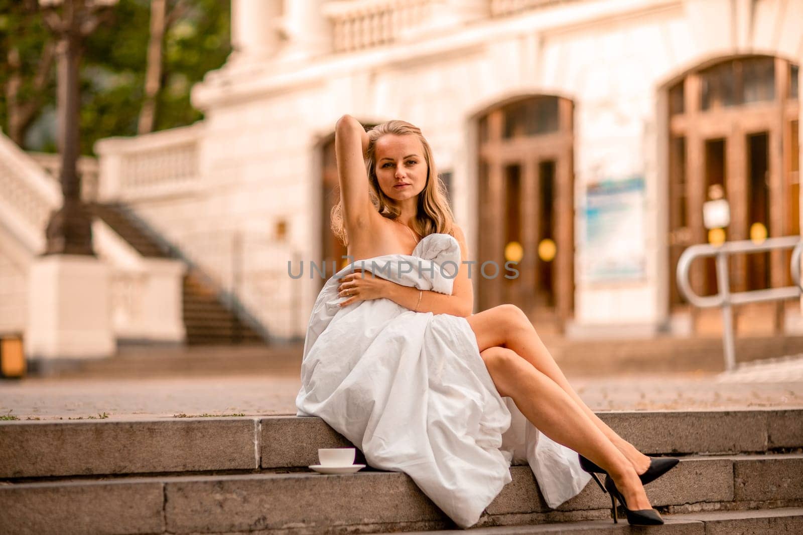 Woman city blanket. Morning in the big city. A blonde woman in a white blanket is enjoying in the city center. Photographed for social media.