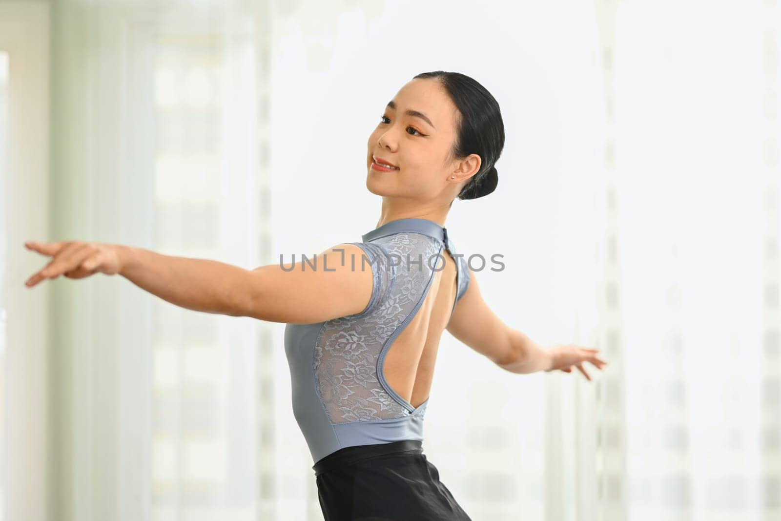 Shot of elegant ballerina practicing dance moves in bright studio. Dance, art, education and flexibility concept.
