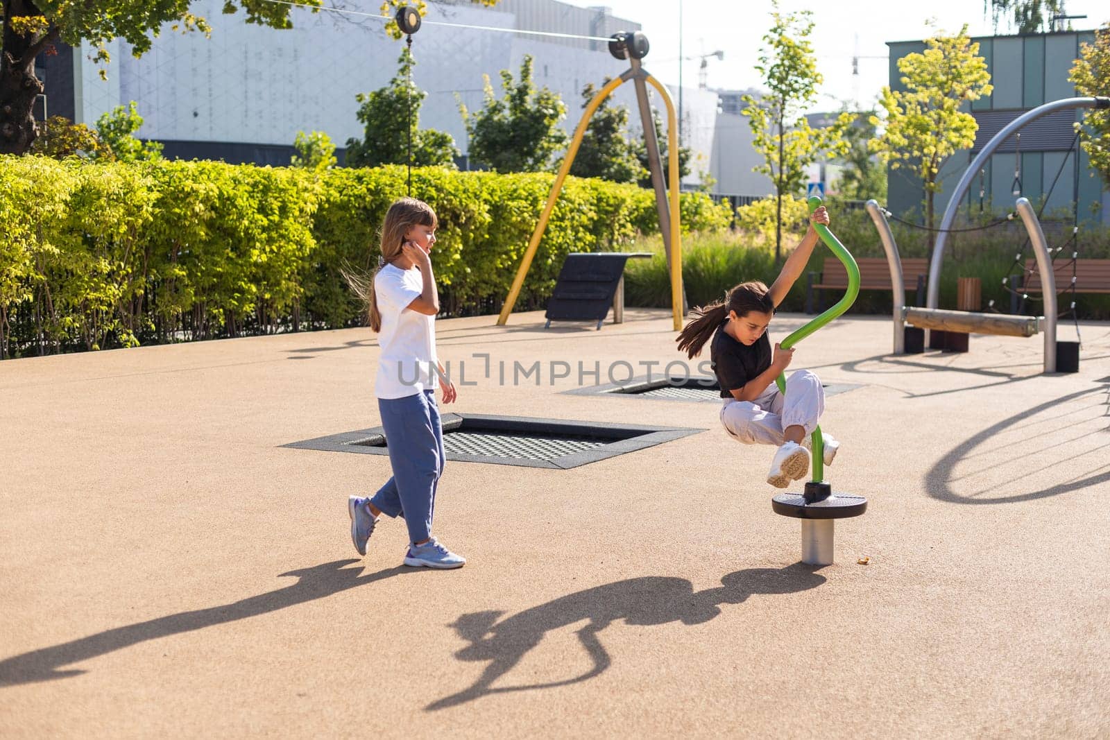 Two children spining on carousel and laughing loudly, hanging out, having fun in playground. happy activities. High quality photo