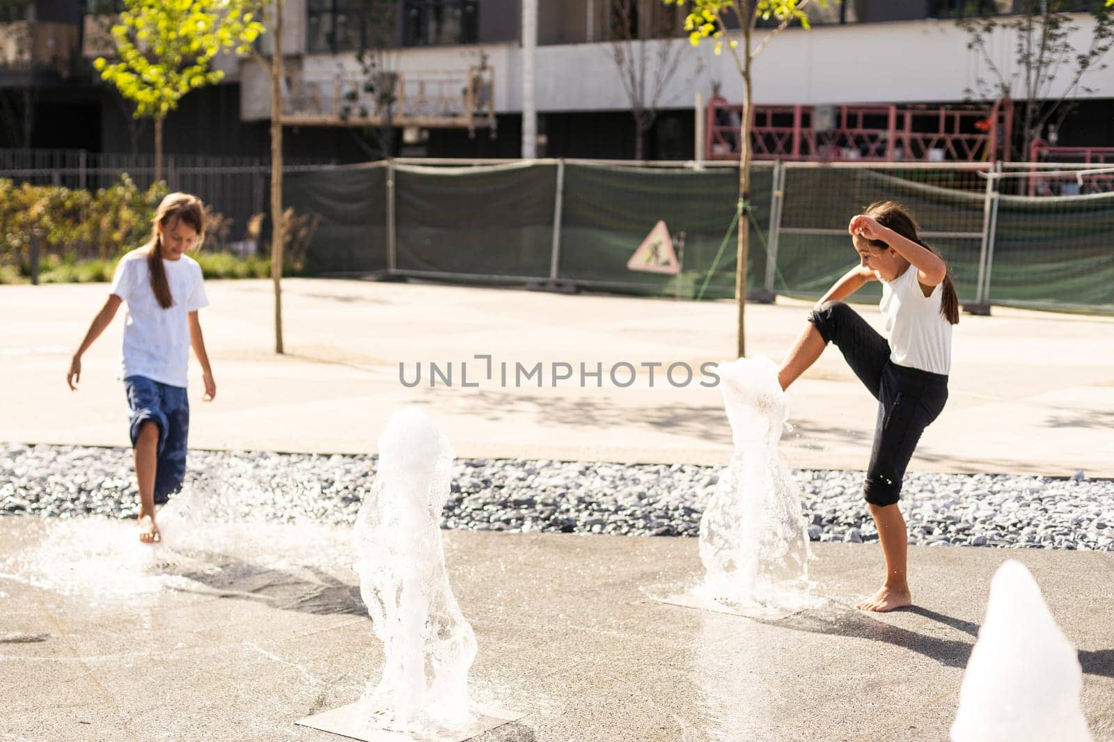 life of children in a modern city - little girl having fun with fountains. High quality photo