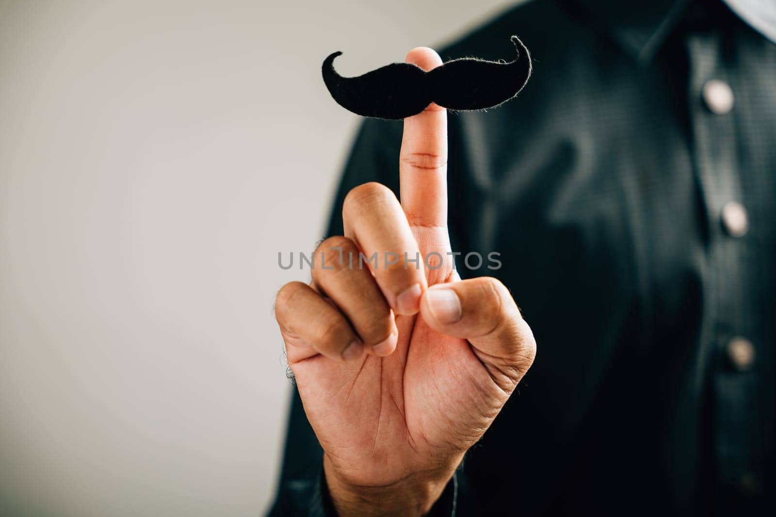 In support of Prostate Cancer Awareness, a man holds a mustache with fun and dedication by Sorapop