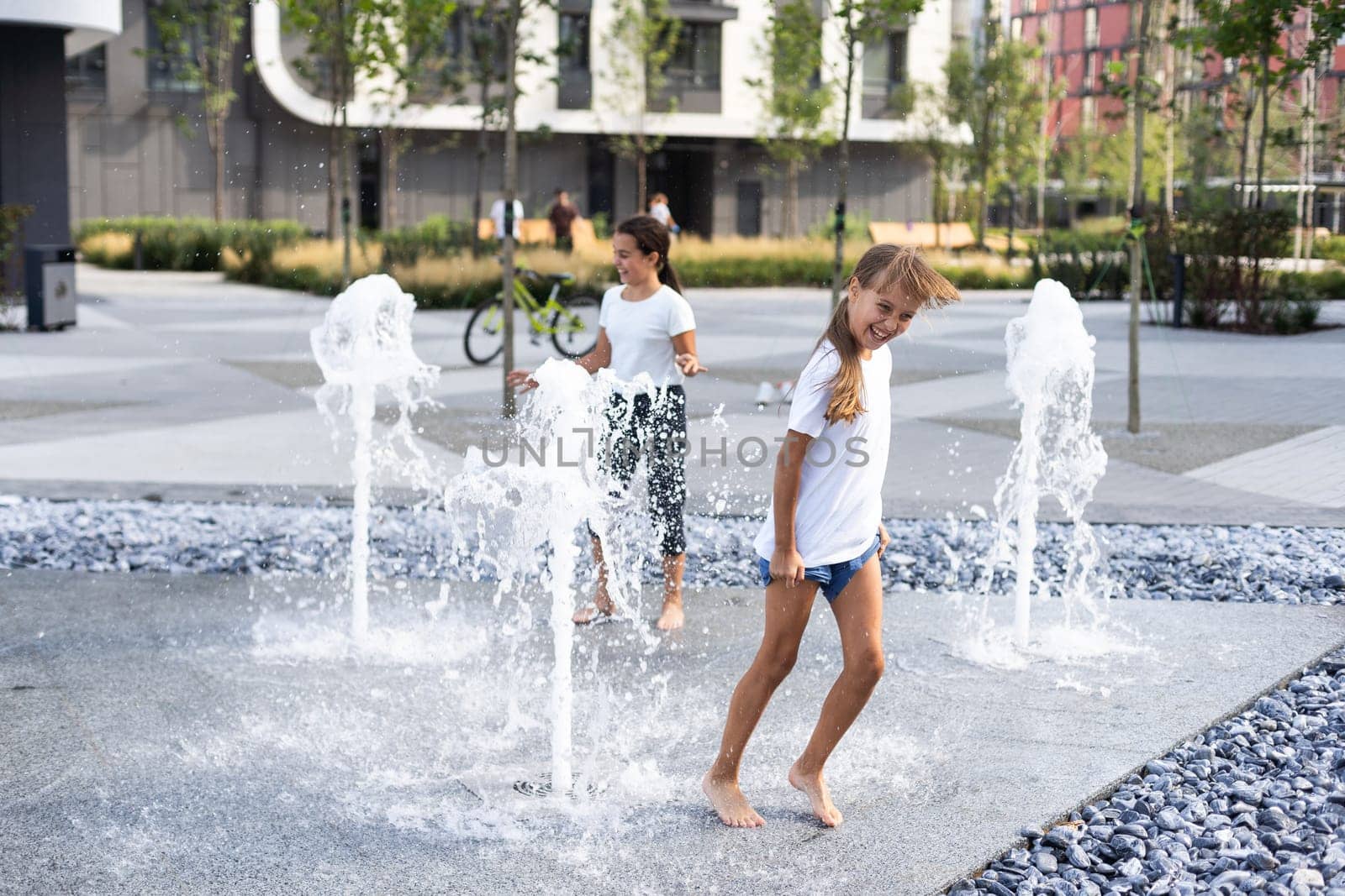 Little girls cool off in a fountain on a hot summer day. High quality photo