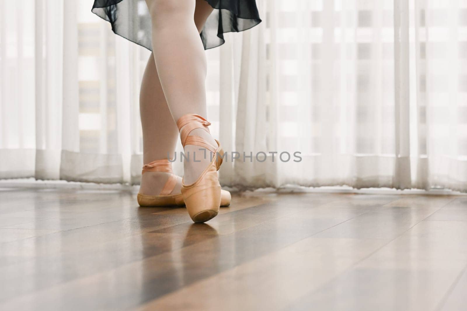 Close up classic ballerina legs in pointe shoes on the wooden floor. Dance, art and active lifestyle concept.