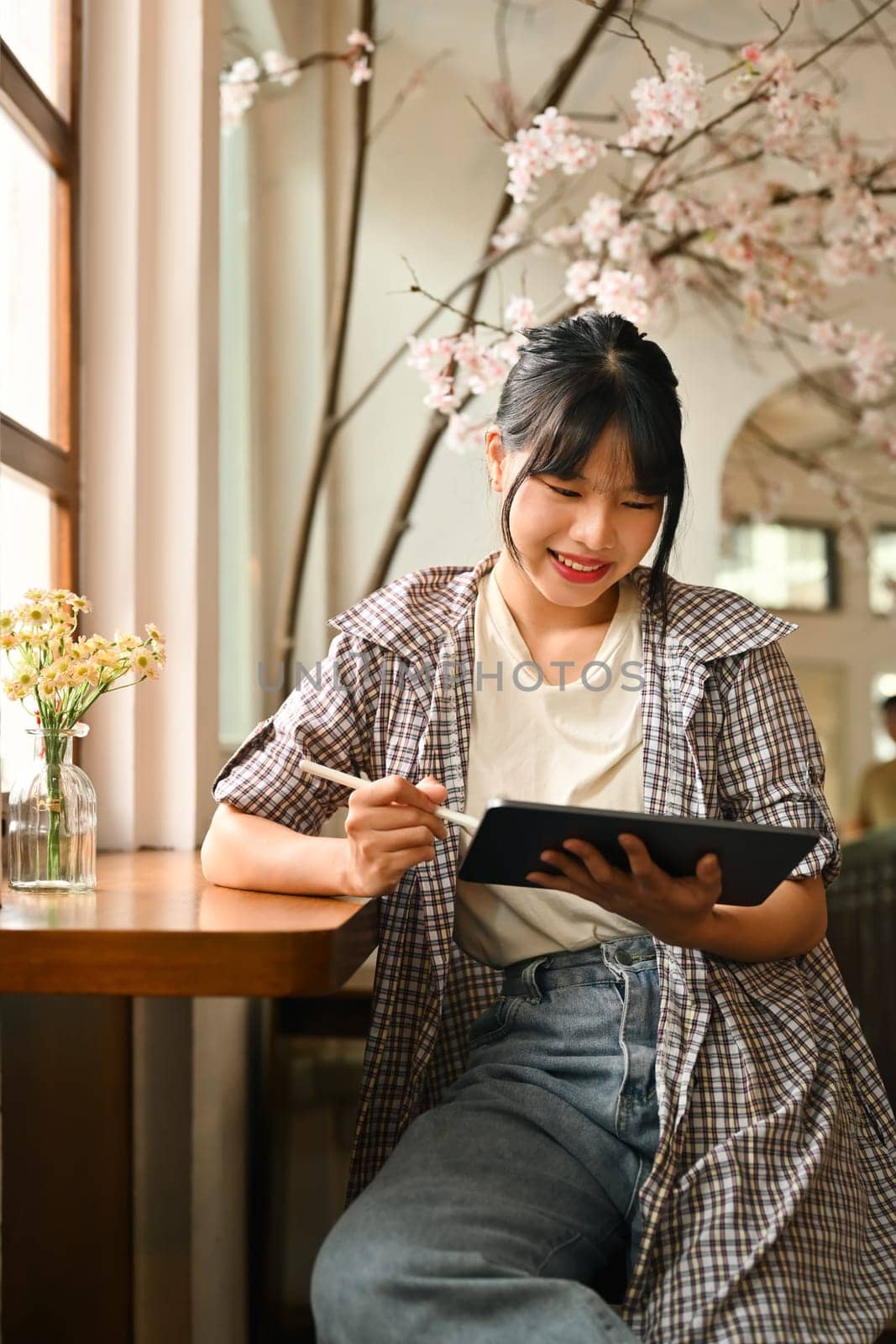 Portrait of satisfied female freelancer using digital tablet, studying remotely or browsing internet at home by prathanchorruangsak