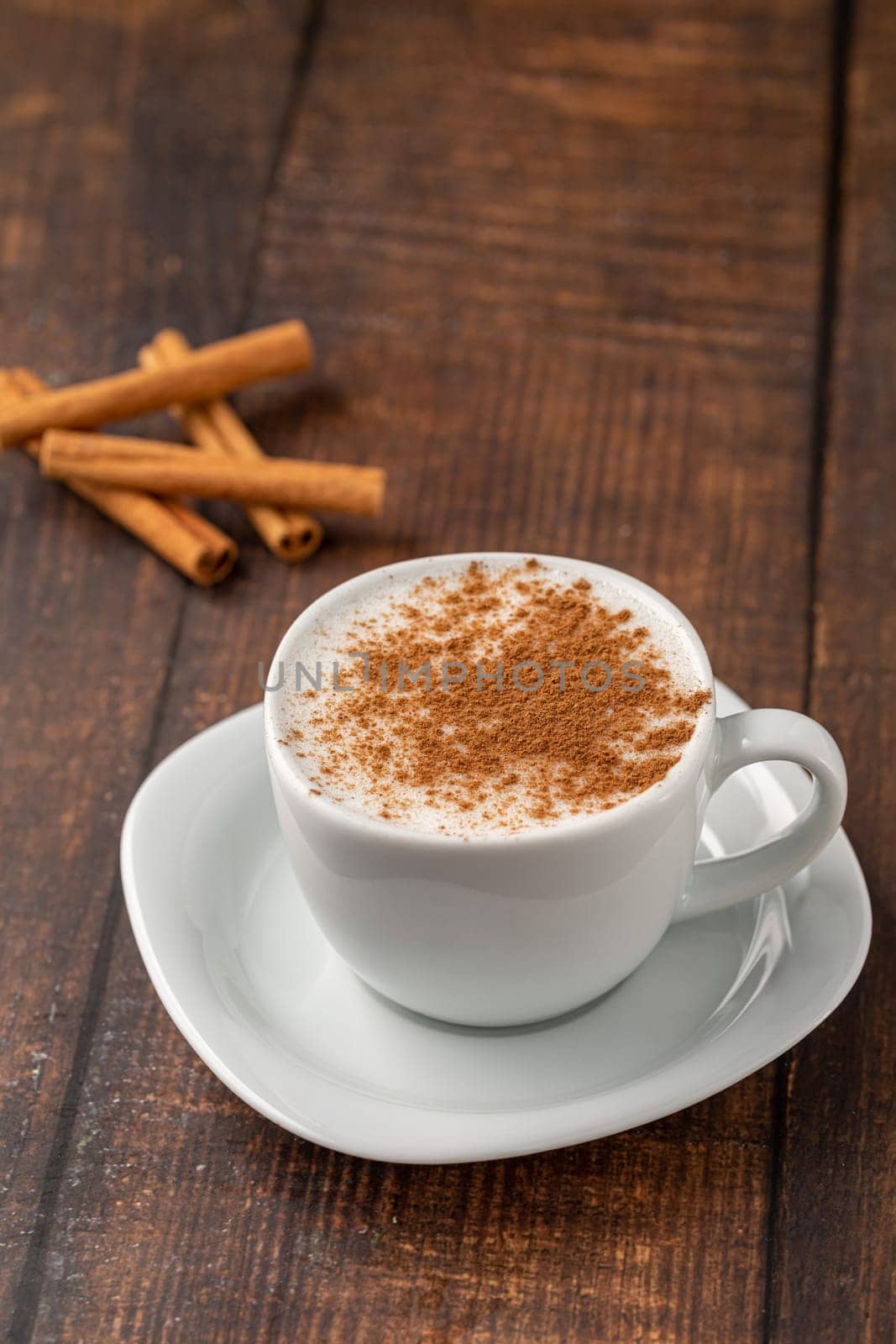 Cinnamon sprinkled salep in a white cup on wooden table by Sonat