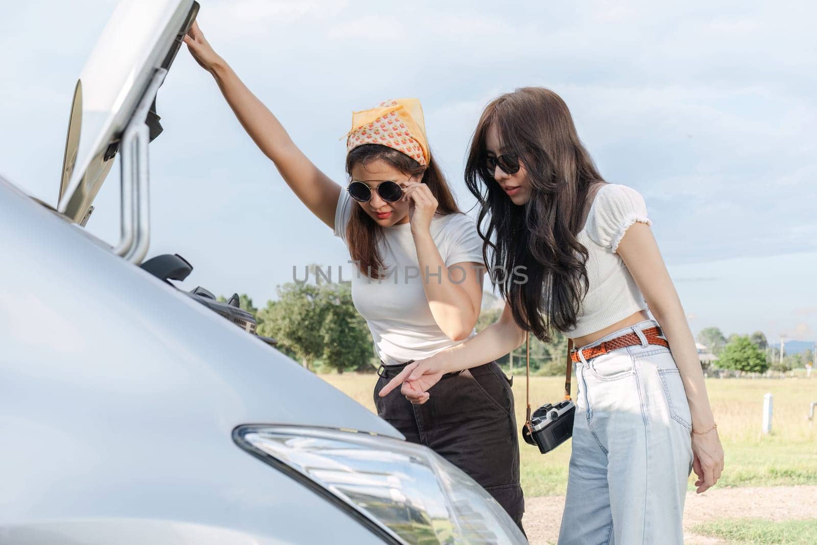 Two young Asian women waiting for insurance assistance I'm stressed out about my car having problems. While traveling together.