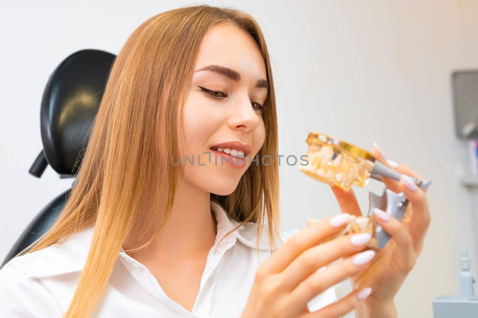 Female patient with plastic jaw model in the dentist office.