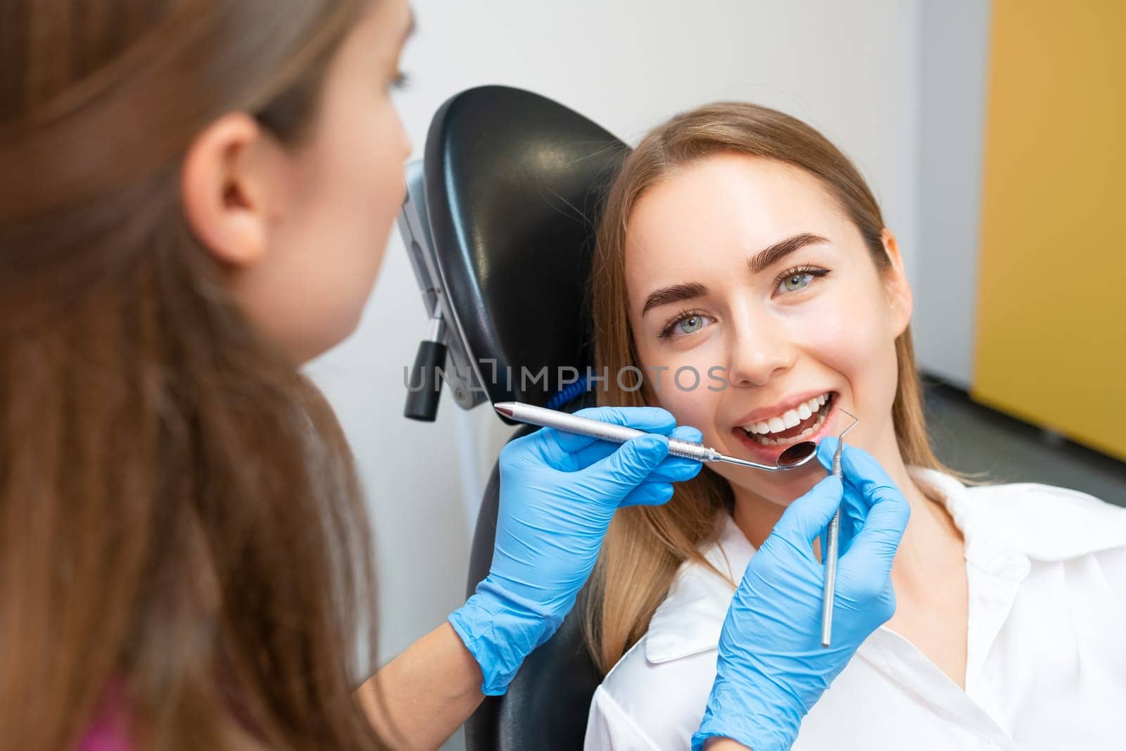 A female patient with an immaculate smile is receiving dental care from the dentist