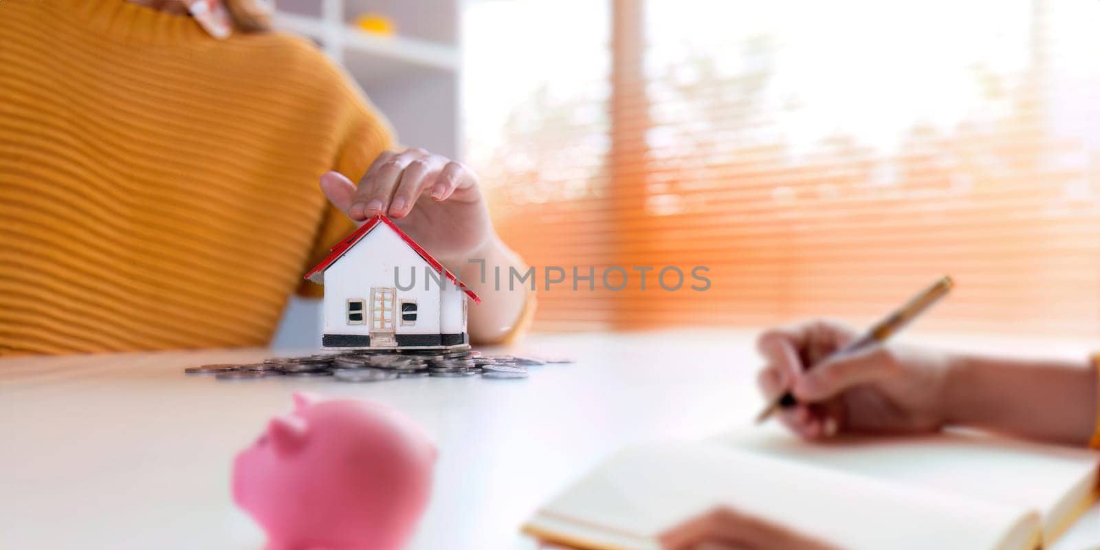 Real estate or property investment. home mortgage loan rate. saving money for retirement concept. Coin stack on international banknotes with house model on table. business growth background by nateemee