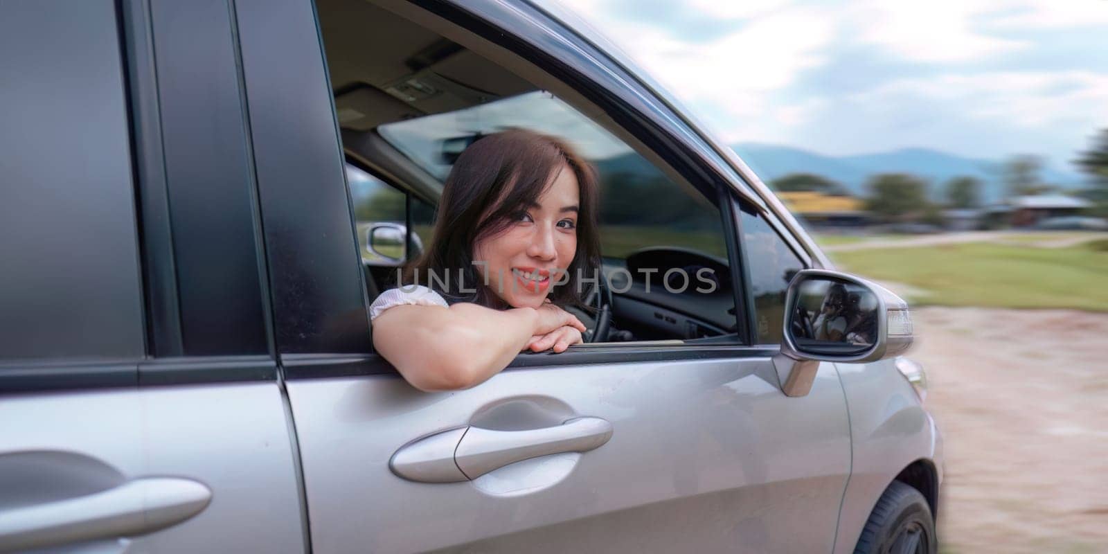 Young smiling woman park the car to car before trip and smiling at camera.