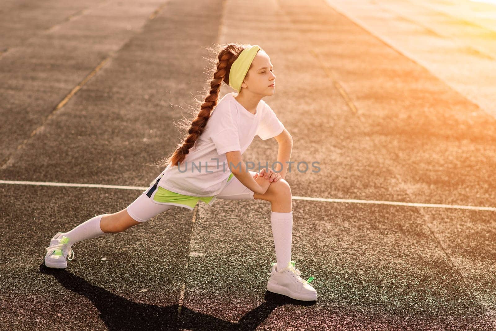 Girl jogging on a sunny summer evening, laying on treadmill, stadium, physical training, back to school, tired.
