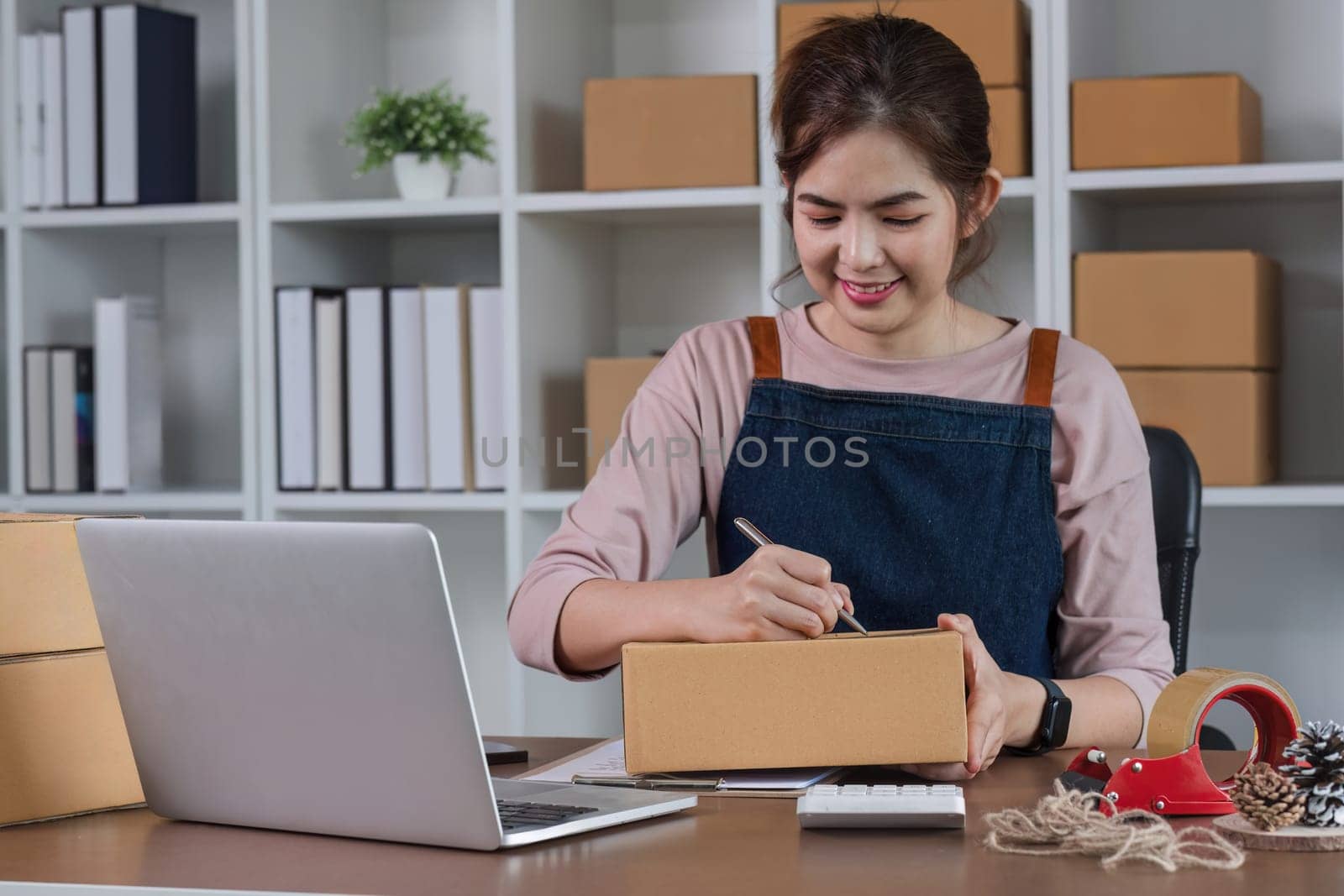 Startup small business entrepreneur SME, asian woman packing cloth in box. Portrait young Asian small business owner home office, online sell marketing delivery, SME e-commerce telemarketing concept.