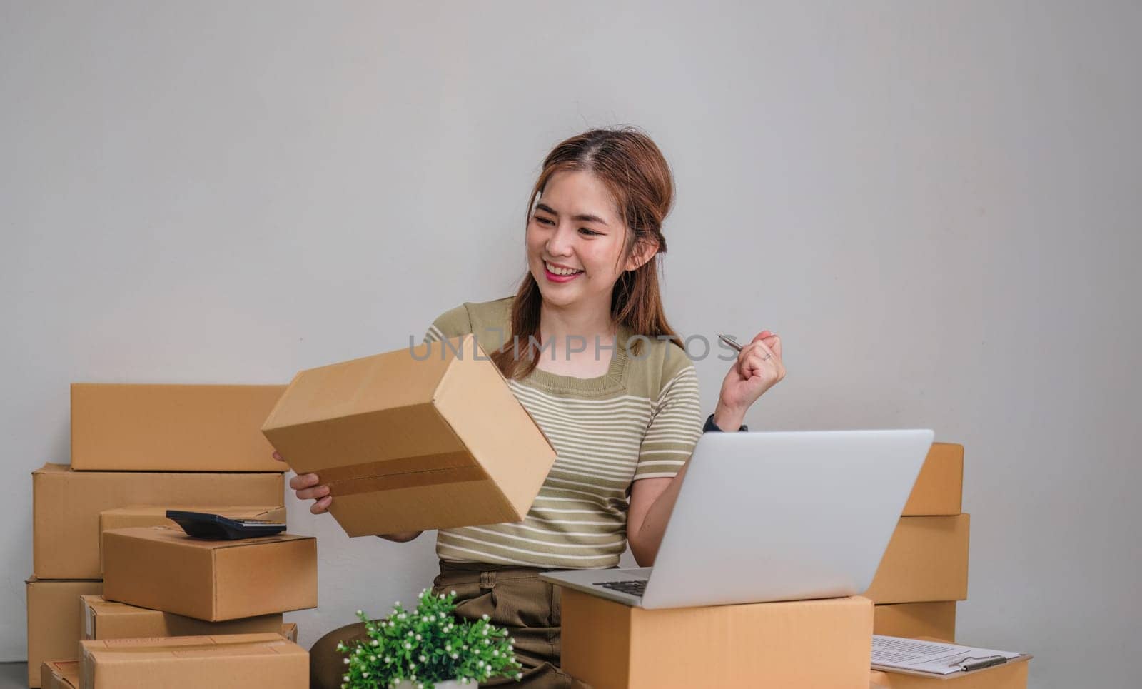 Happy young Asian woman entrepreneur, Smile for sales success after checking order from online by wichayada