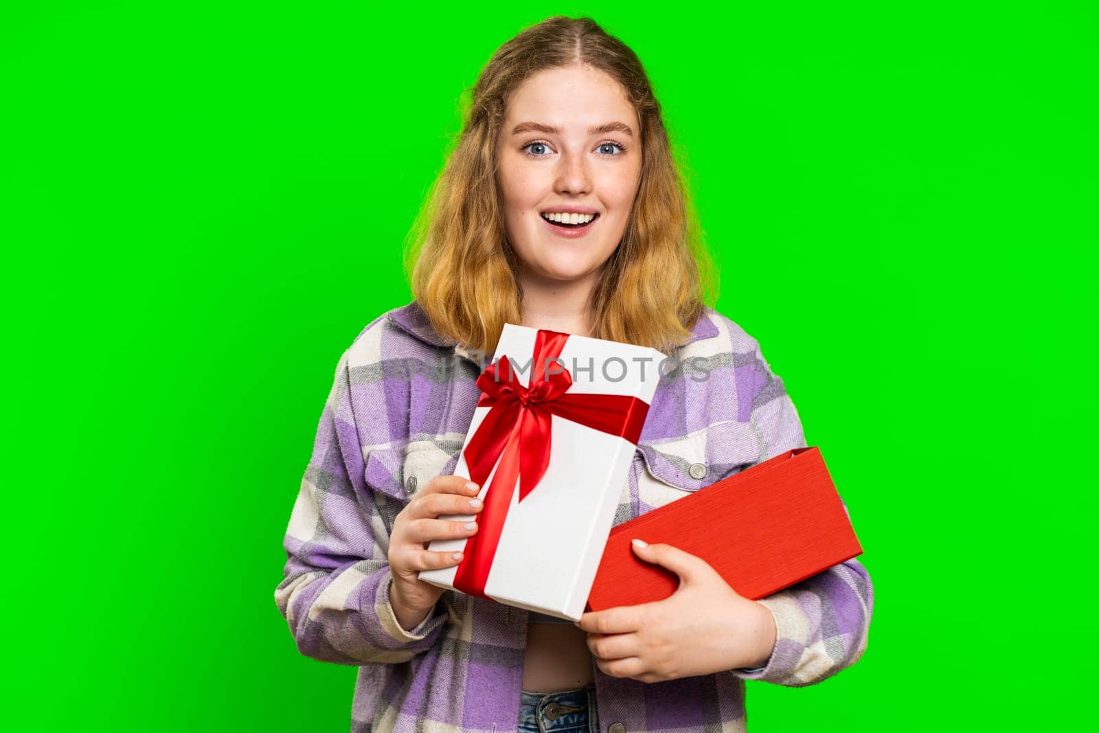 Happy caucasian woman opening birthday gift box with red ribbon. Holidays surprise concept. Smiling redhead girl receiving great wrapped present celebrating isolated on green chroma key background