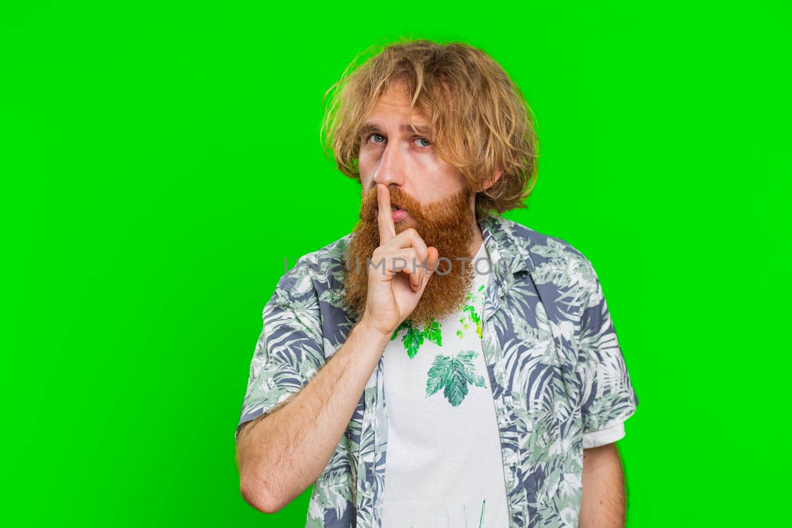 Shh be quiet please. Young man presses index finger to lips makes silence gesture sign do not tells secret, stop talk gossip confidential privacy. Redhead bearded guy isolated on chroma key background