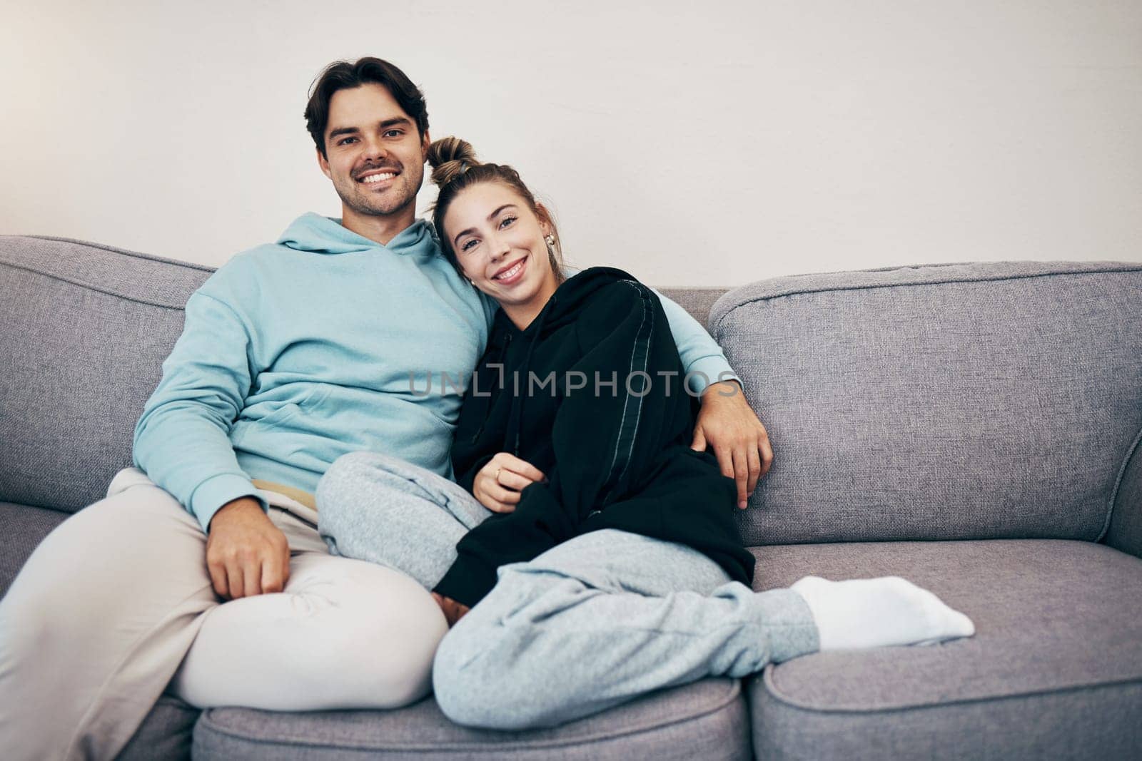 Portrait, relax and smile with a couple on a sofa in the living room of their home together for bonding. Love, hug or date with a happy man and woman in their apartment for romance or relationship by YuriArcurs