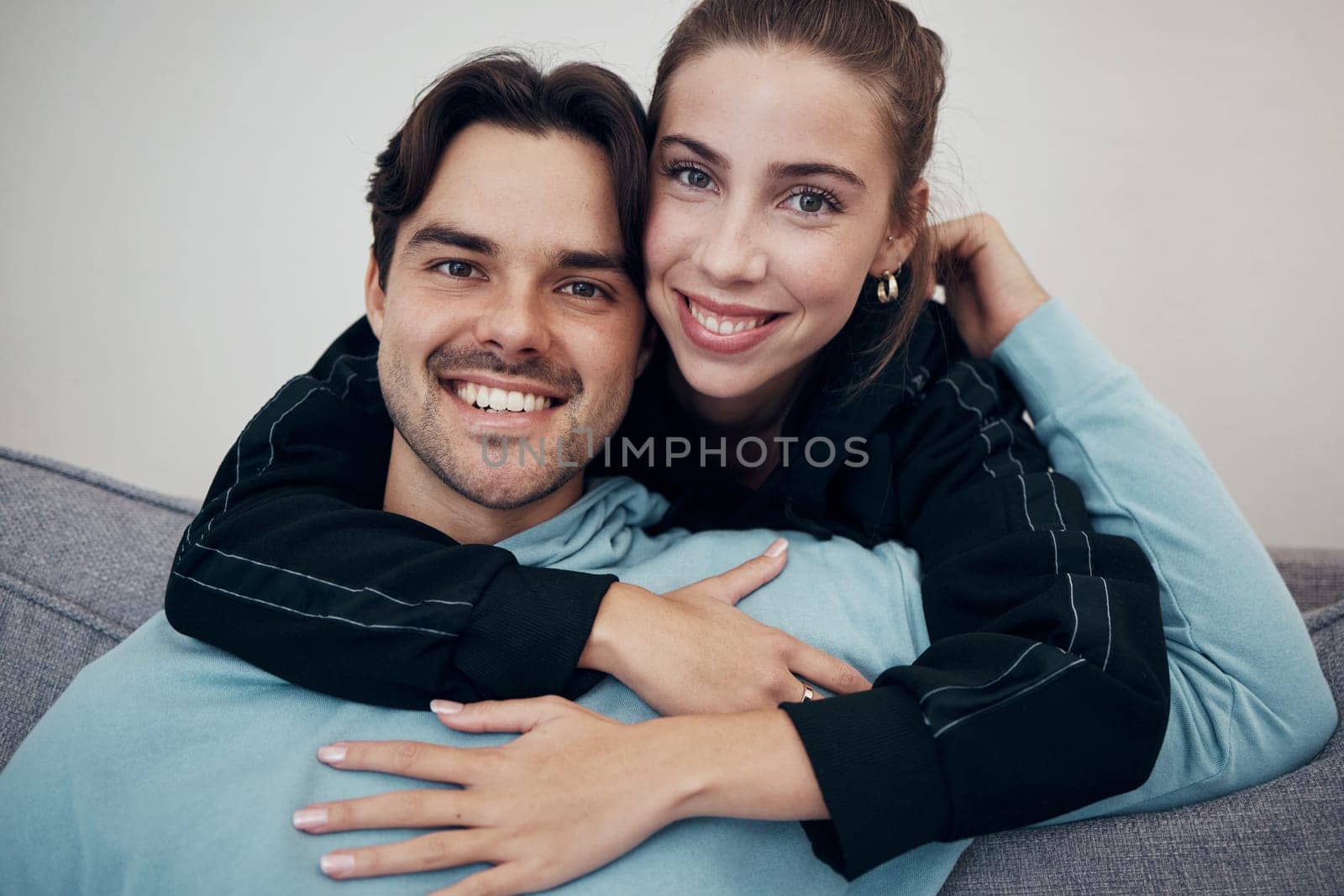 Portrait, hug and smile with a couple on a sofa in the living room of their home together for bonding. Relax, love or date with a happy man and woman in their apartment for romance or relationship by YuriArcurs