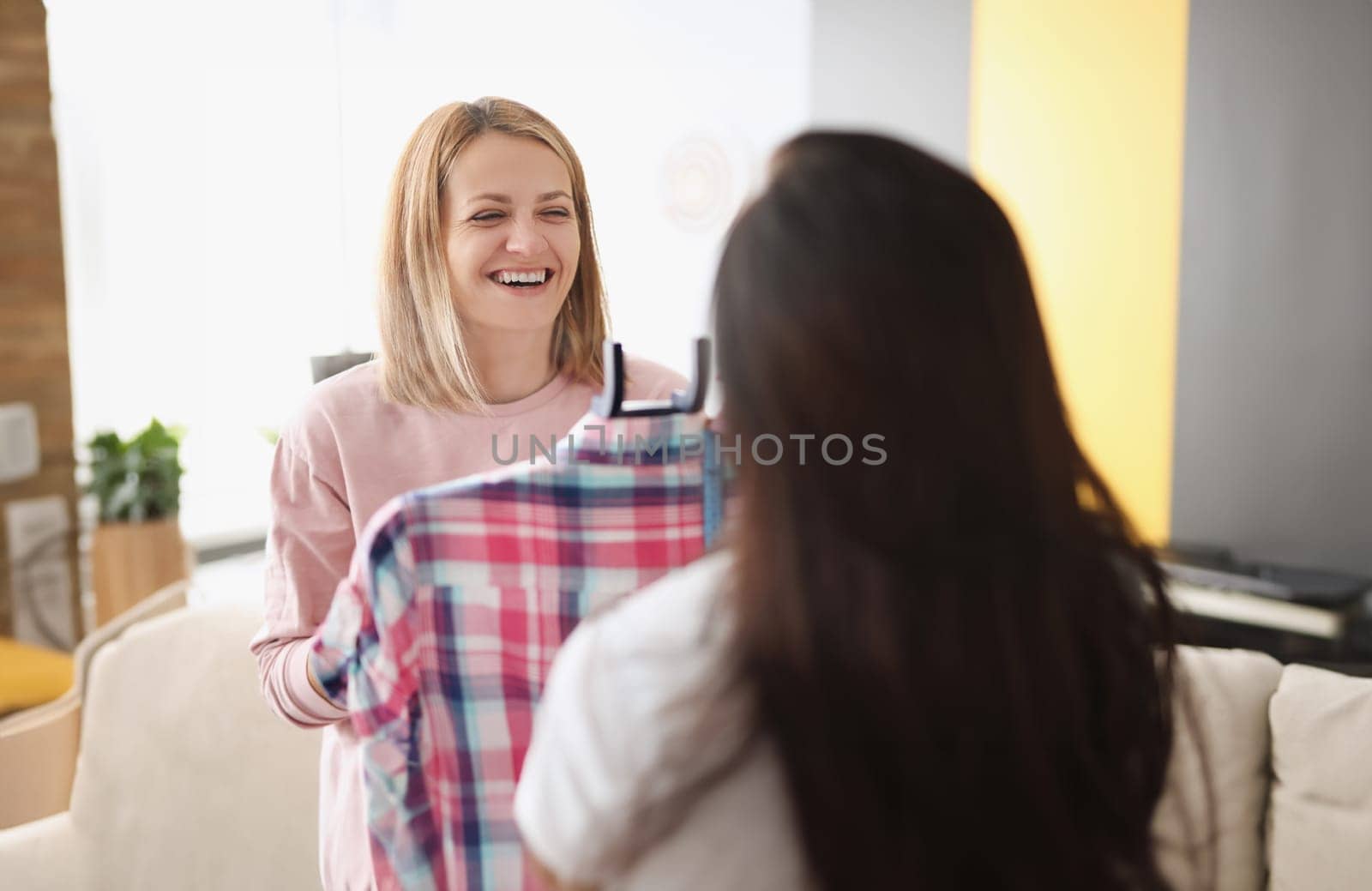 Smiling woman demonstrates clothes on hanger to client by kuprevich