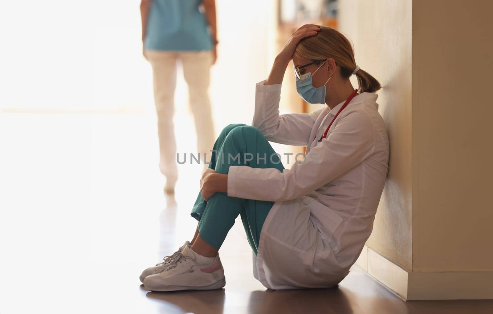 Frustrated doctor sits in hospital corridor. Medical error and accident concept
