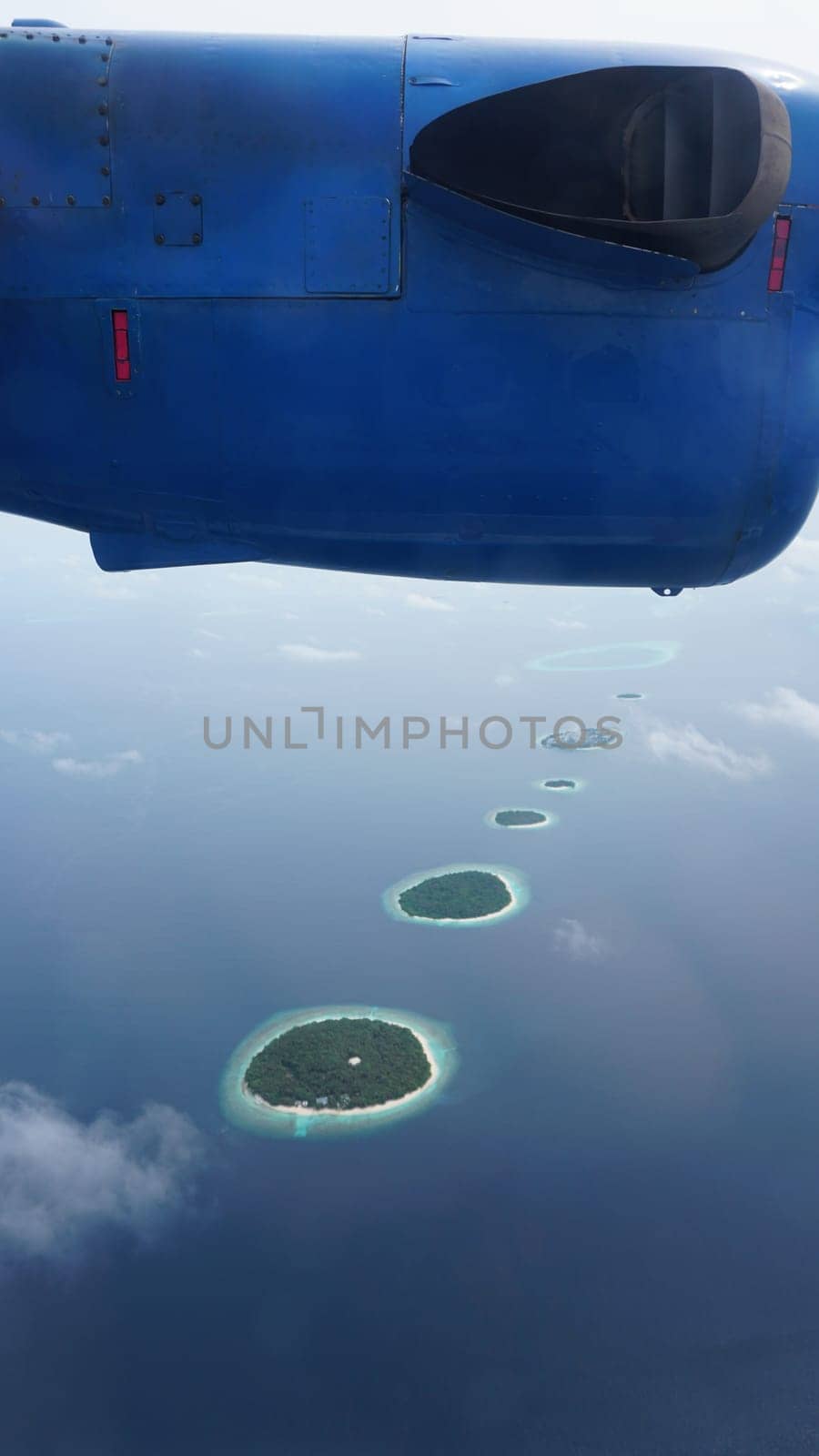 Airplane soaring over a stunning chain of small tropical islands, surrounded by the sparkling turquoise waters of the indian ocean, creating a picturesque scene in the maldives