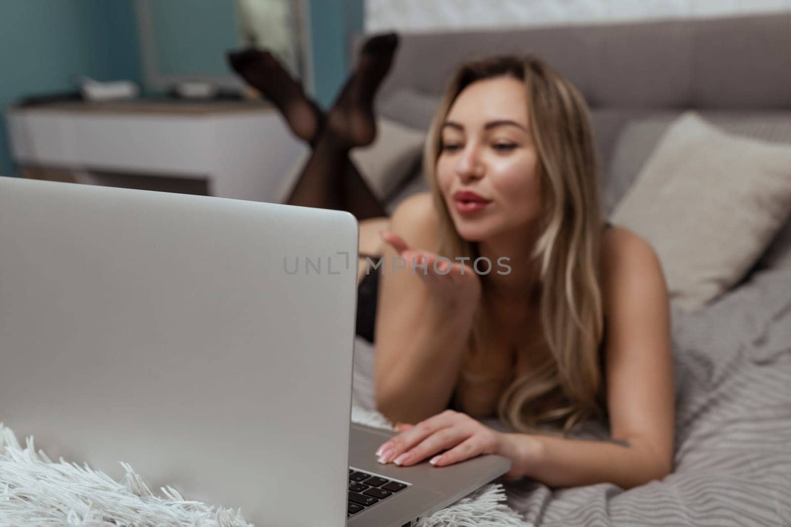 A beautiful, young girl shoots a webcam, blows a kiss into the camera, works as a model. The concept of online flirting, sex on the Internet.