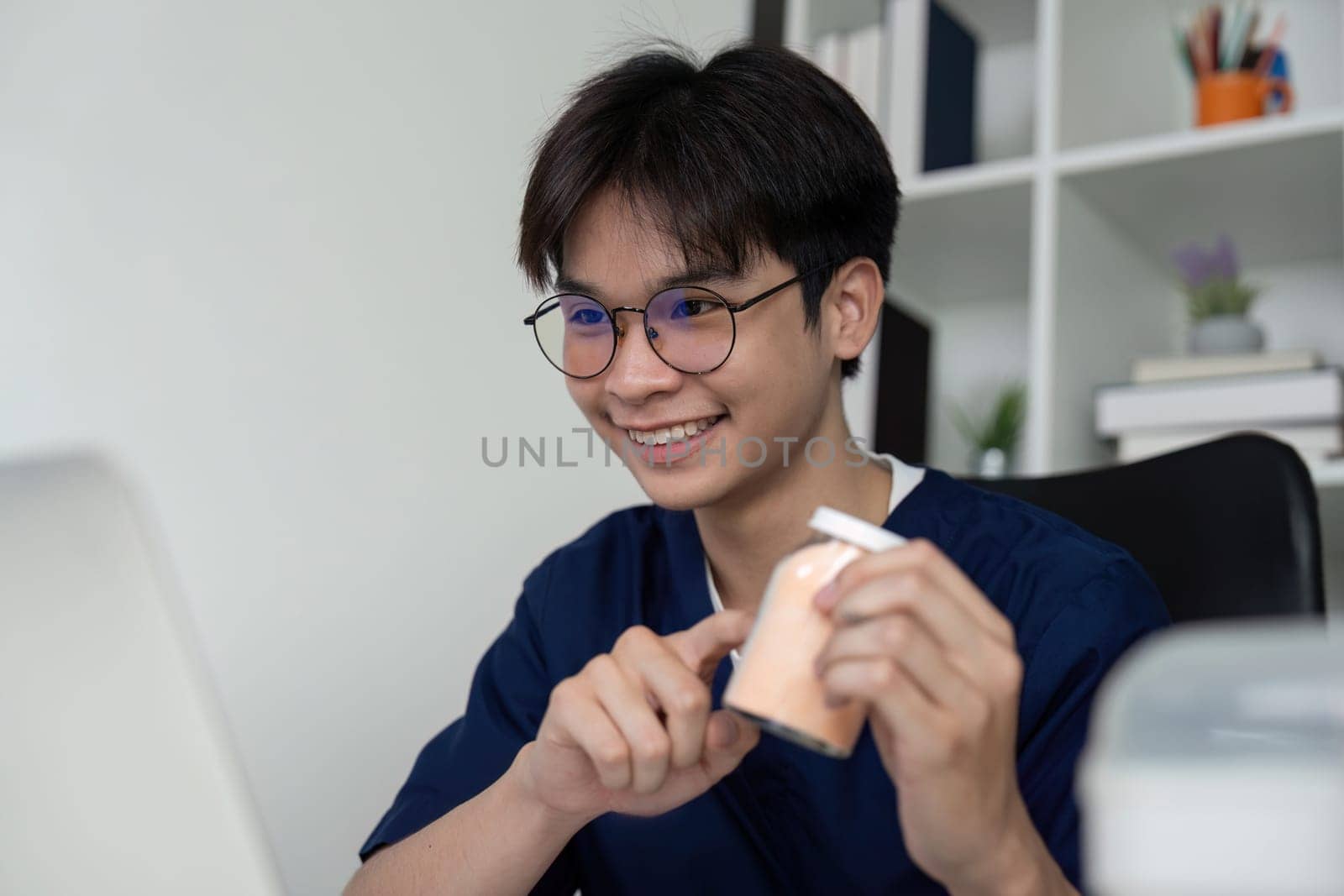A cheerful medical student shows medication bottles during an online study session, reflecting enthusiasm for healthcare and learning.