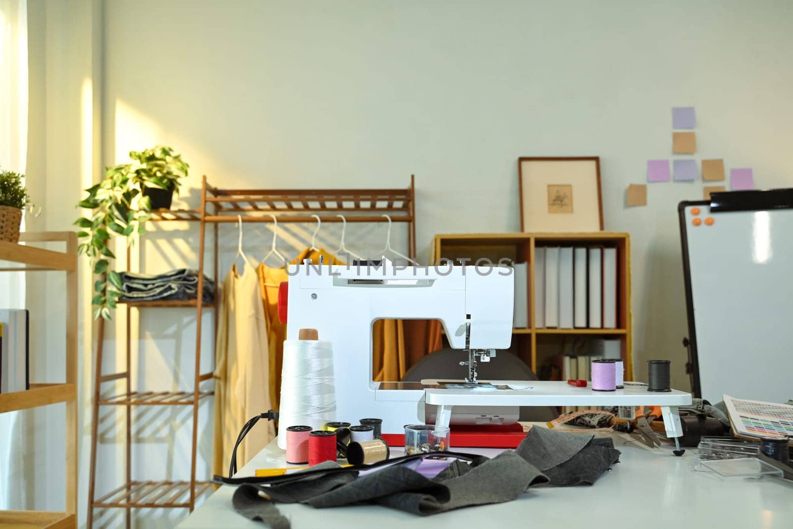 Fashion design studio with sewing tools, colorful thread spools and fabric swatches.