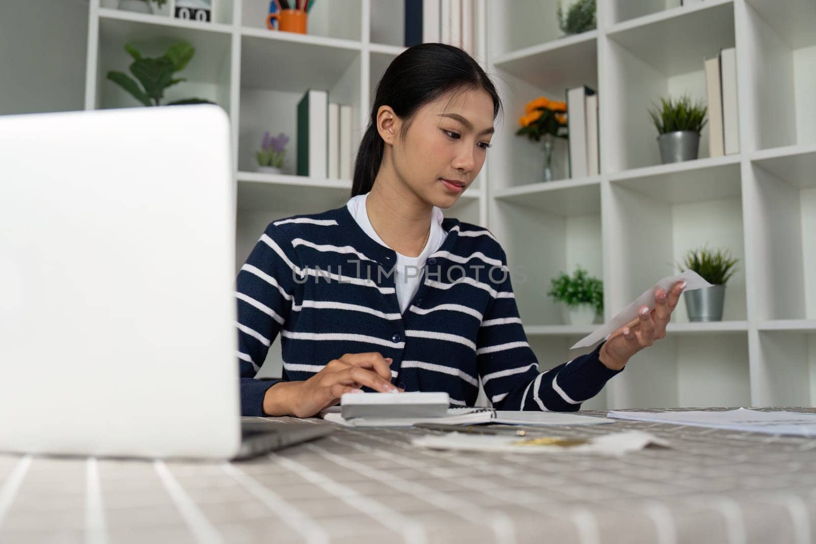 A woman reviews her bills and uses a calculator to manage her expenses, highlighting personal finance practices.