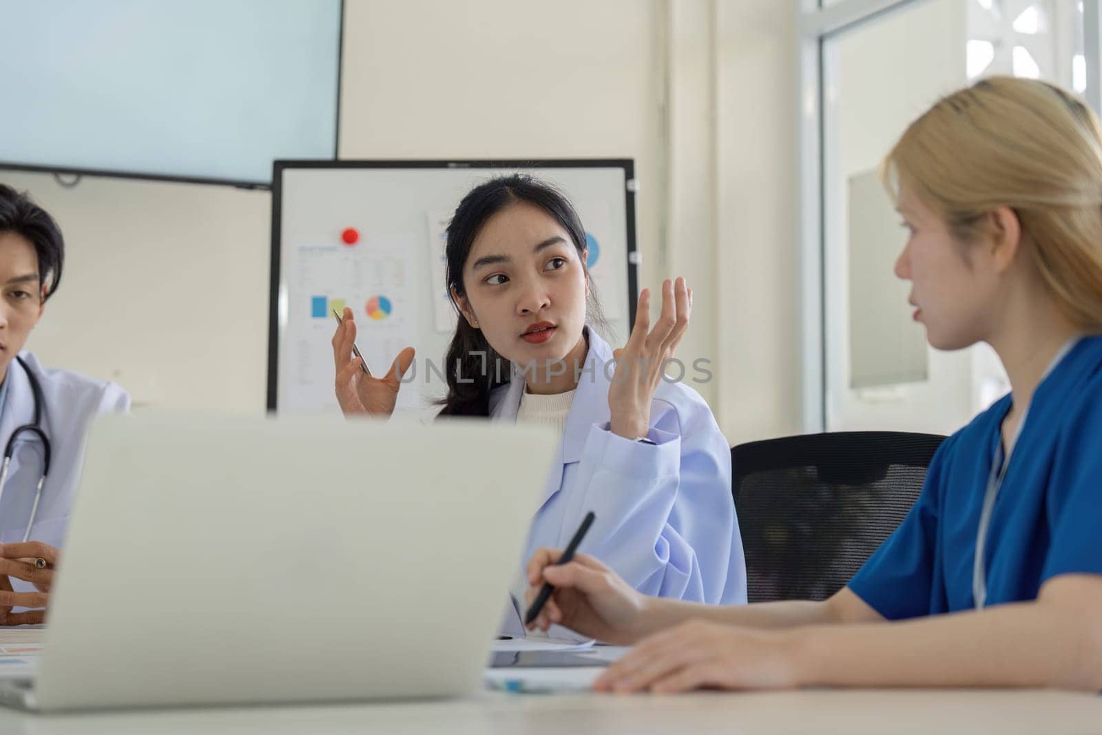 A diverse group of healthcare professionals engages in a meeting to analyze patient care strategies and improve outcomes.