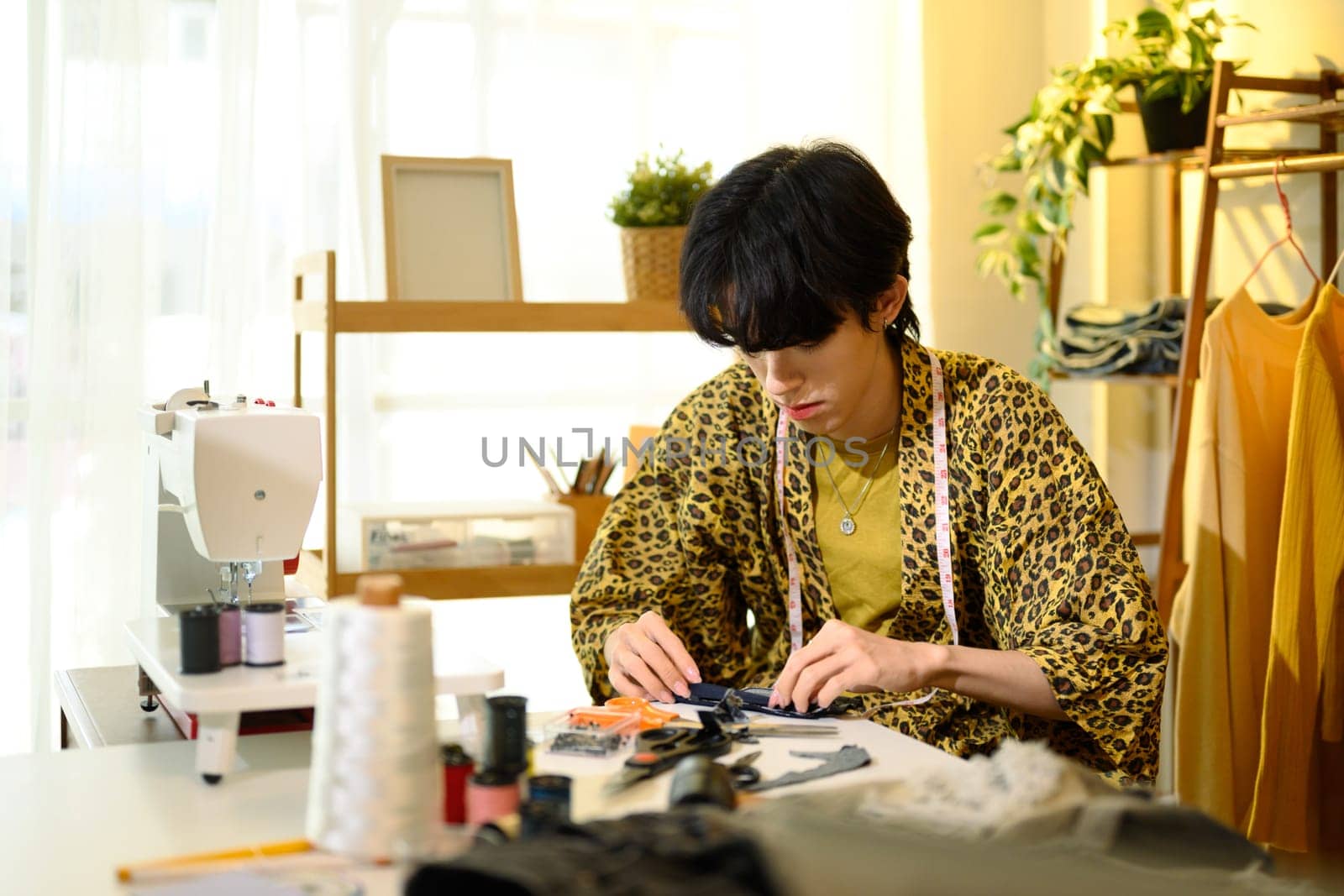Young fashion designer working on a clothing project in stylish studio.