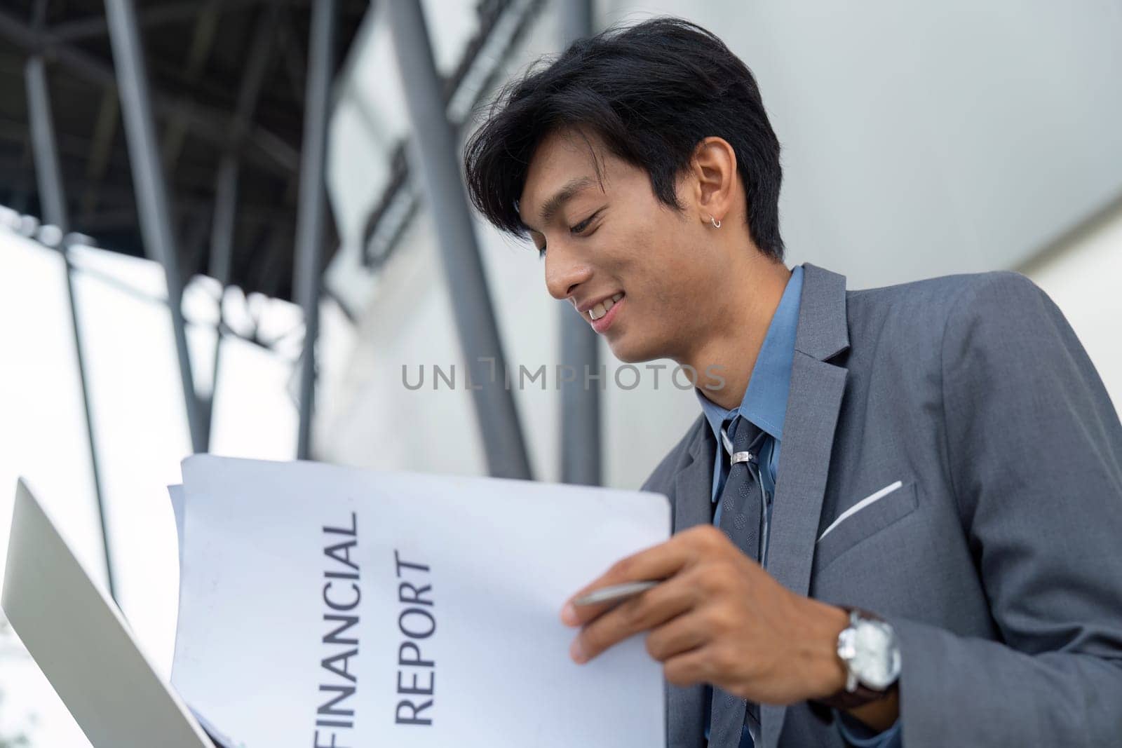 A young businessman analyzes a financial report outdoors, highlighting a blend of professionalism and nature.