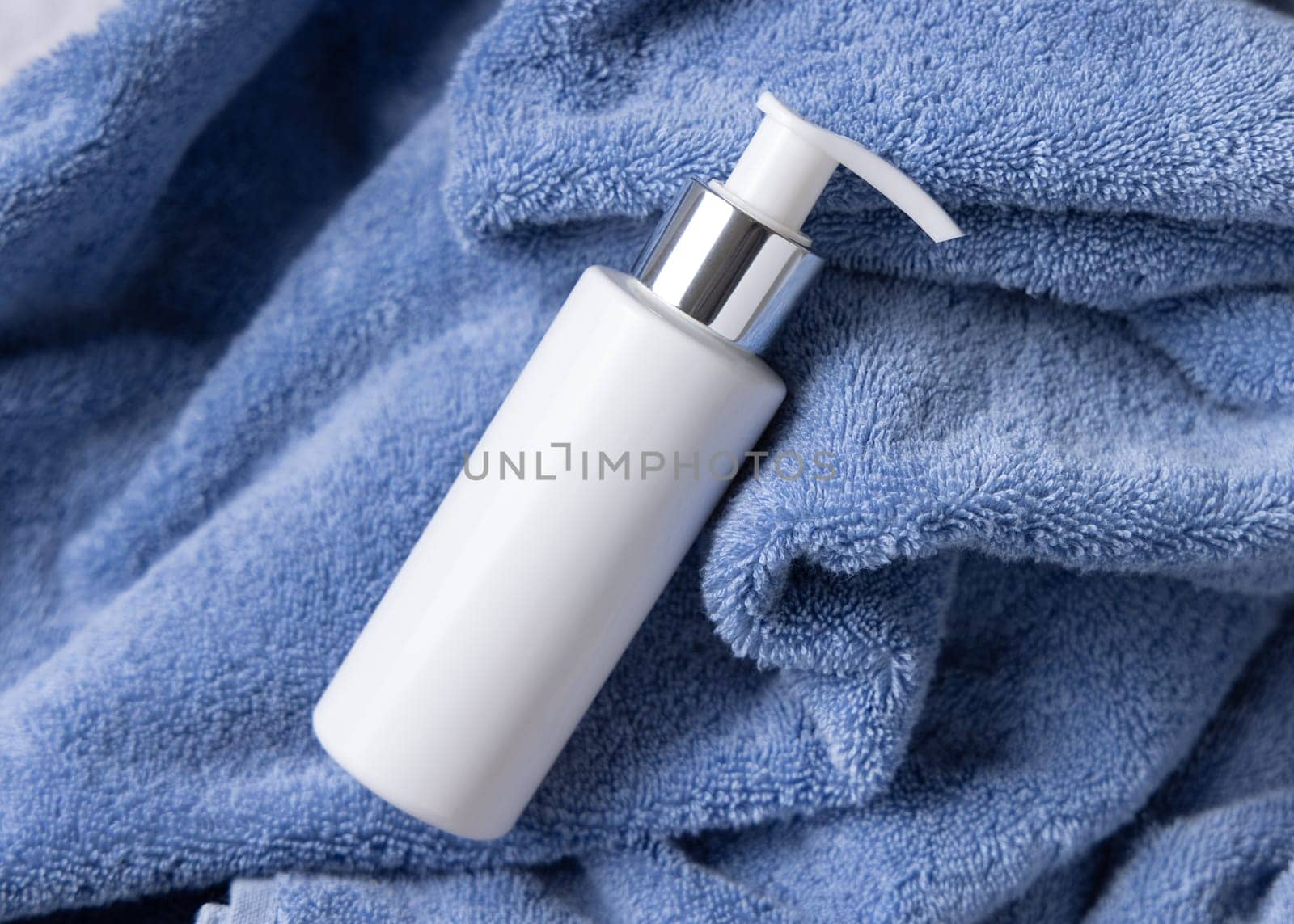 White blank one pump bottle on blue towel in bathroom closeuptop view, brand packaging mockup. Natural handmade cosmetic product - cream, lotion or soap for daily face or handcare, copy space