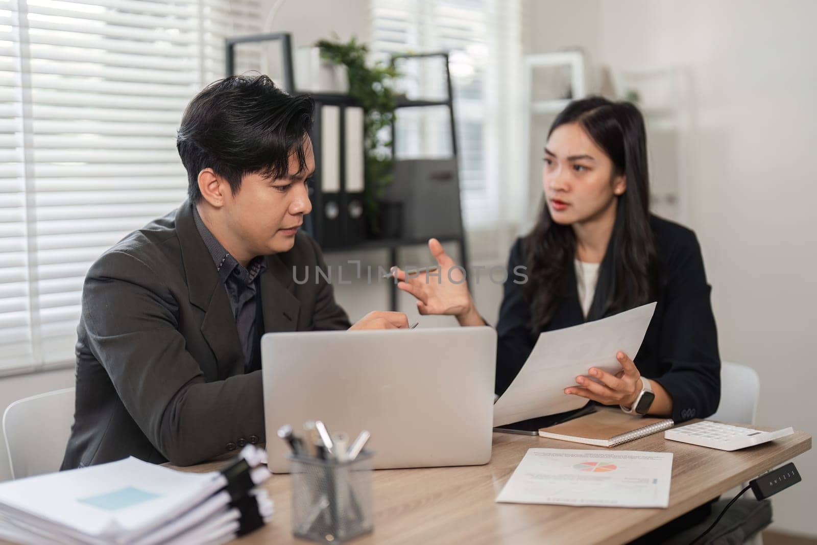 Two business partners review financial data and engage in strategic discussions in a modern office environment.