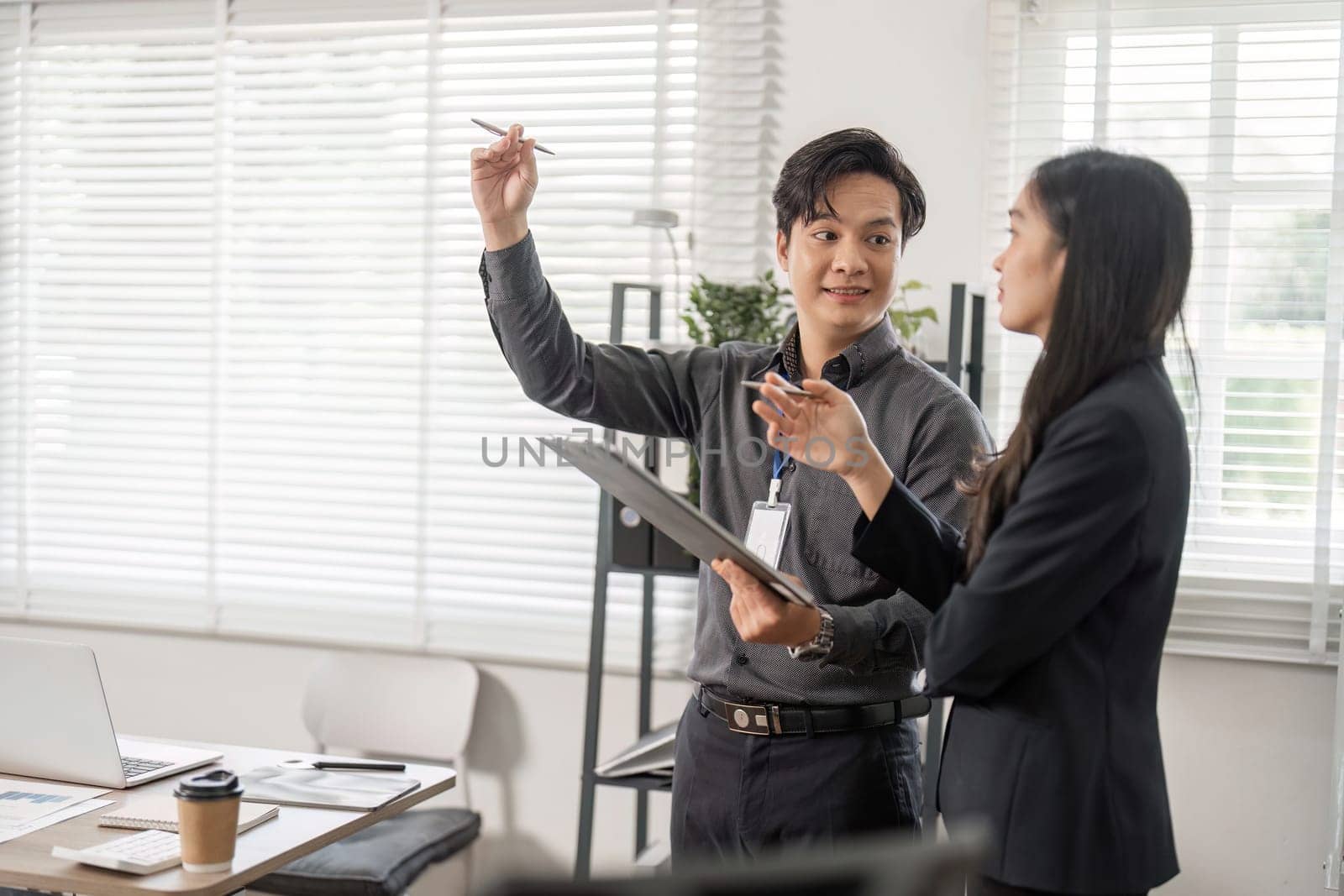 Two business professionals joyfully celebrate a success in their modern office, emphasizing teamwork and collaboration.