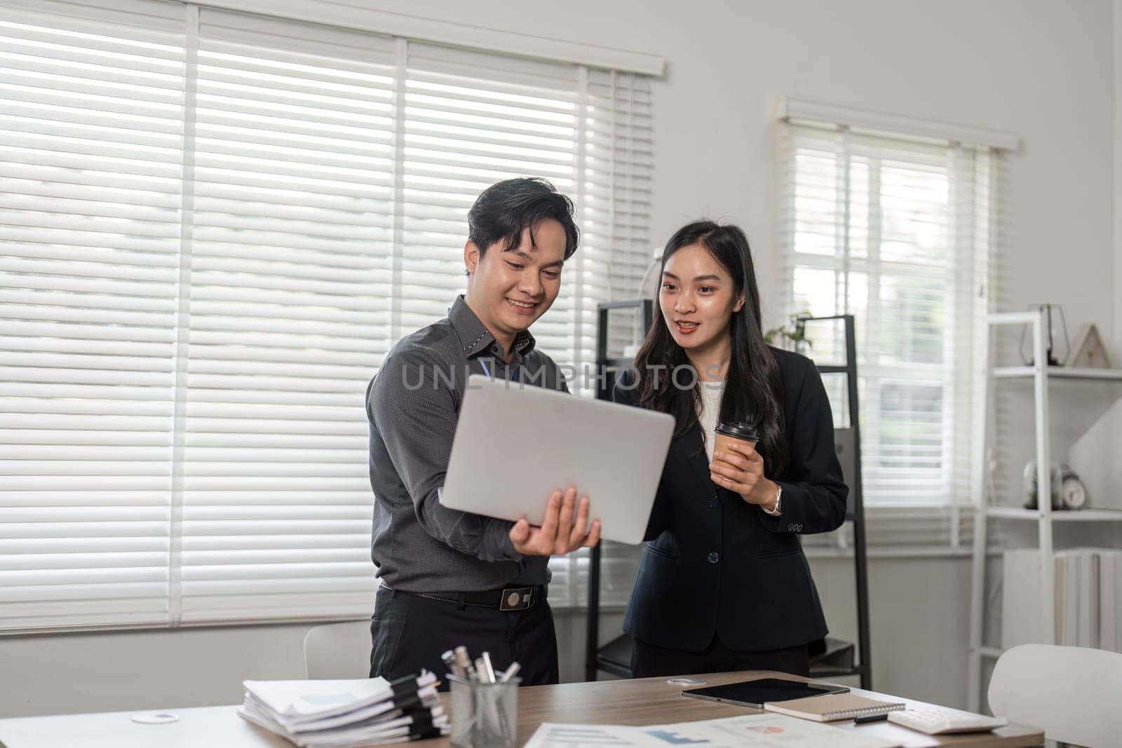 Two professionals discuss project progress, showcasing teamwork and collaboration in a bright office environment.