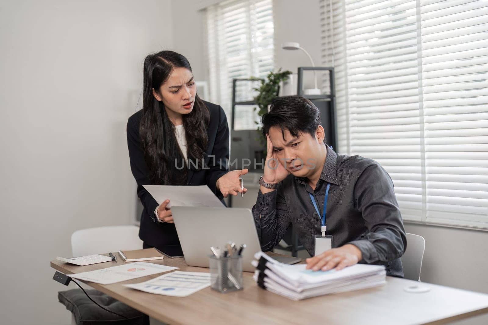 A woman expresses frustration to a man in an office setting, highlighting workplace challenges and communication issues.