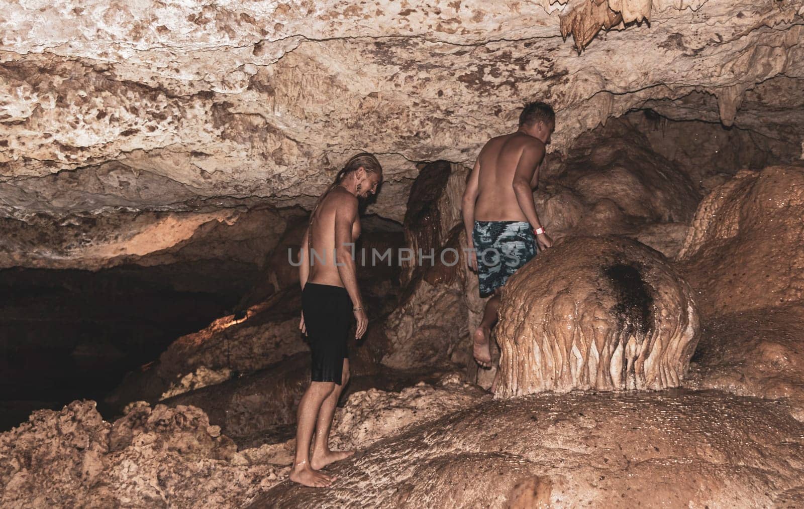 Mean male tourists friendsare posing and climbing in the turquoise green blue water and rocks in cenote Yaxmulito in Tulum Quintana Roo Mexico.