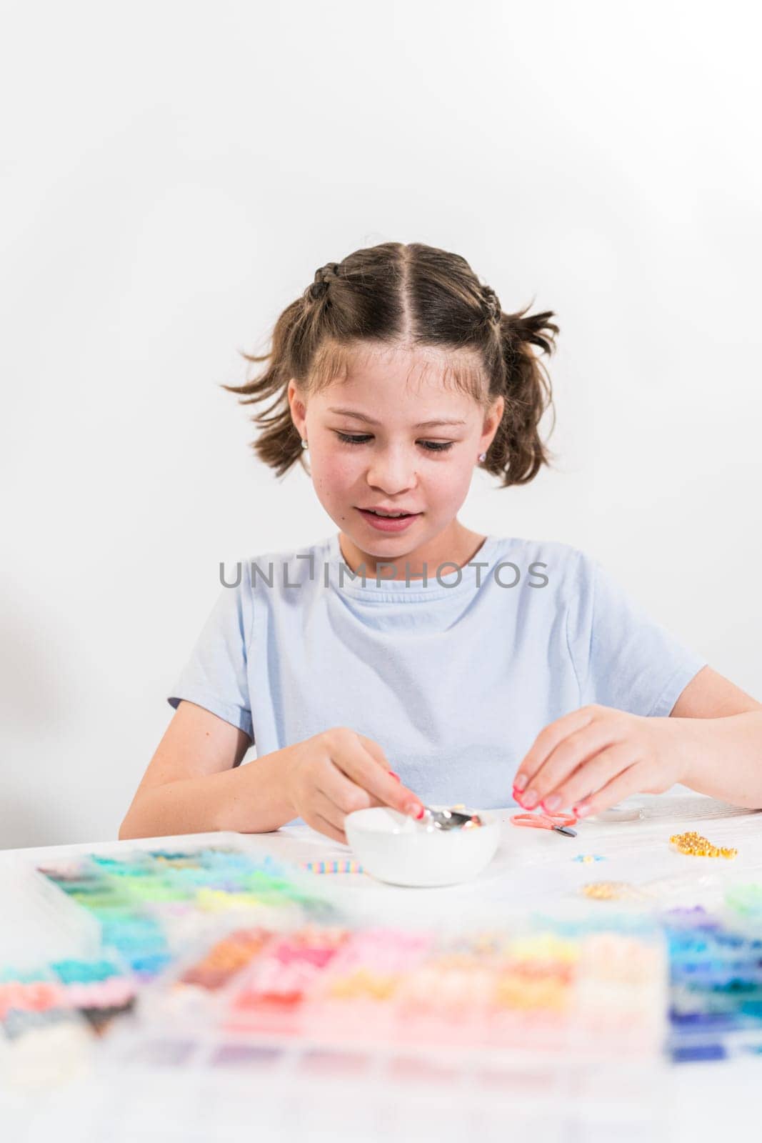 Little girl enjoys crafting colorful bracelets with vibrant clay beads set.