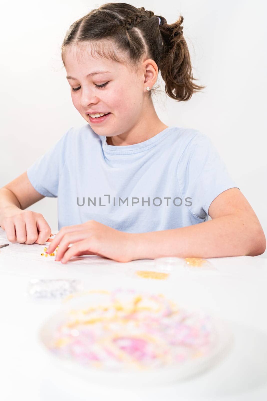 Little girl enjoys crafting colorful bracelets with vibrant clay beads set.